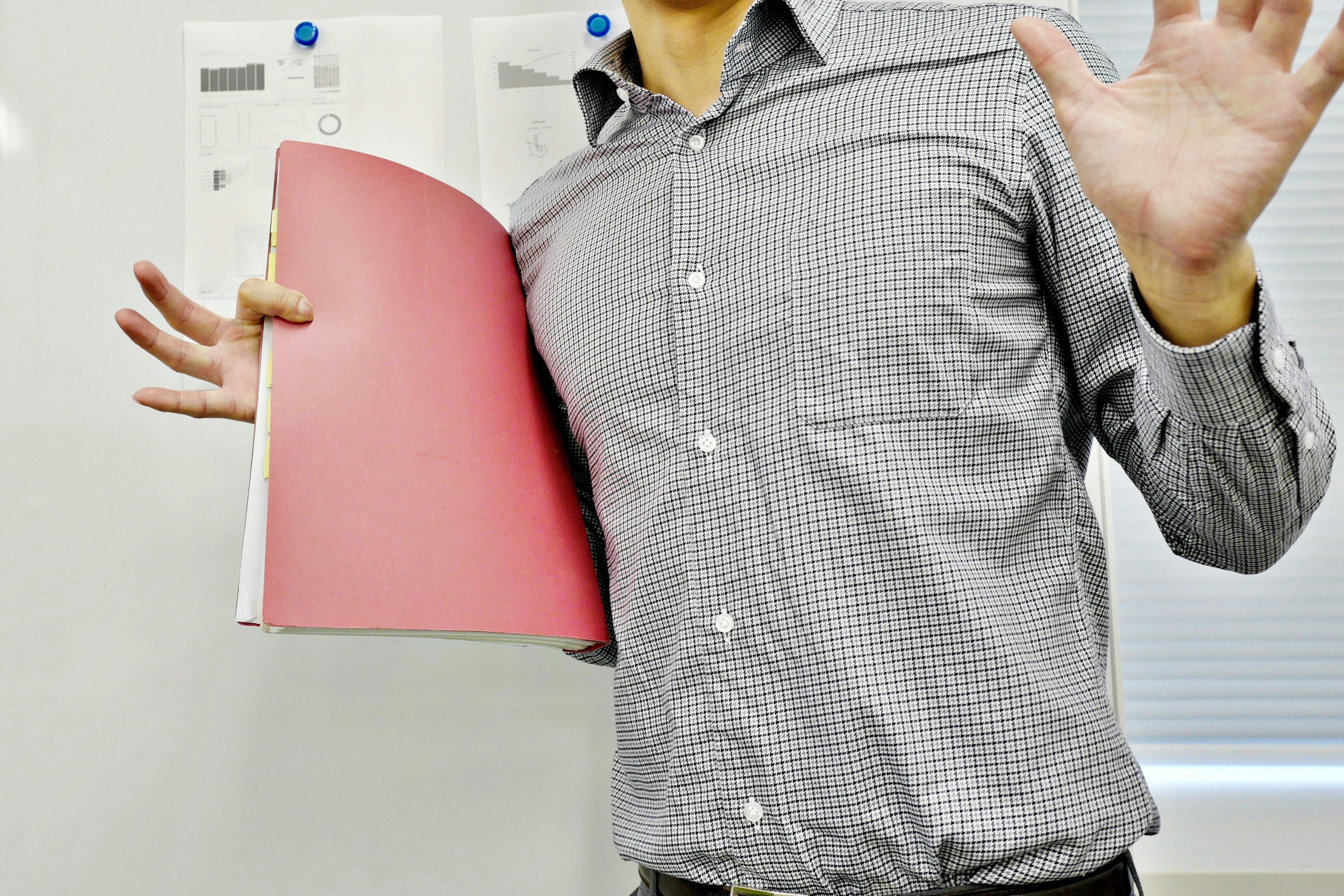 Man in checkered shirt holding a red folder