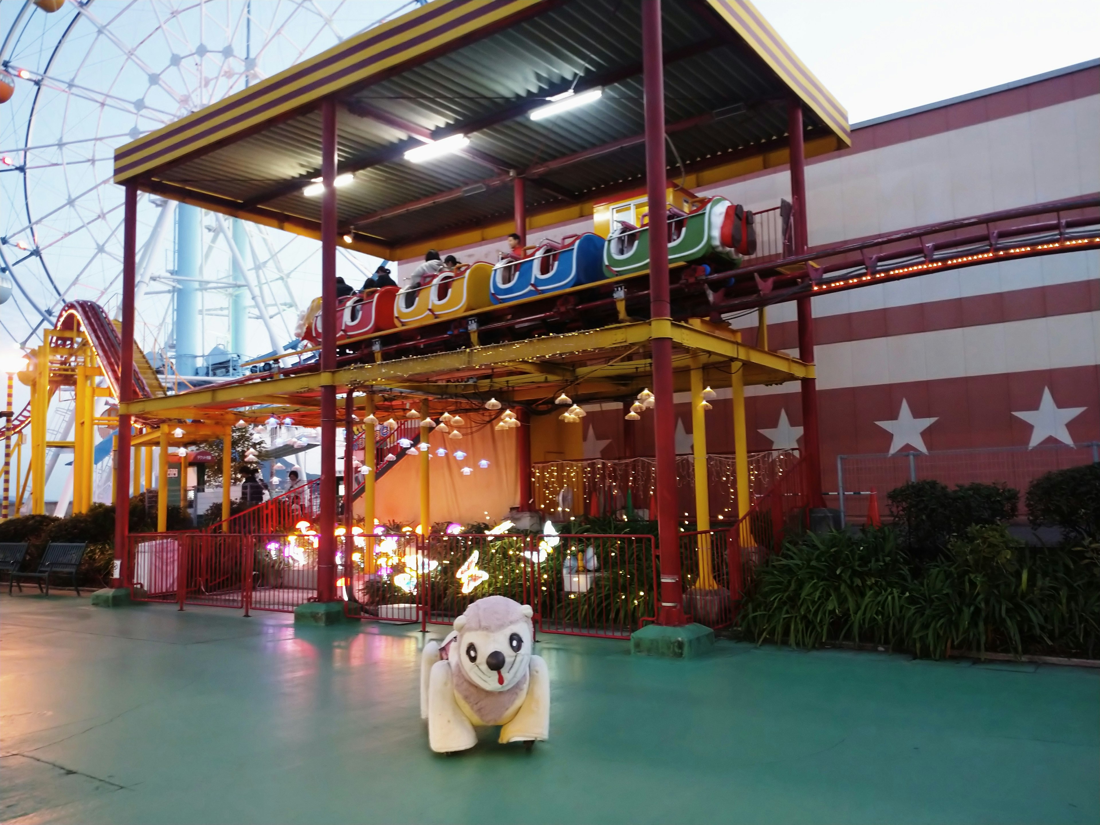 Night scene of an amusement park featuring a colorful attraction and a white bear character