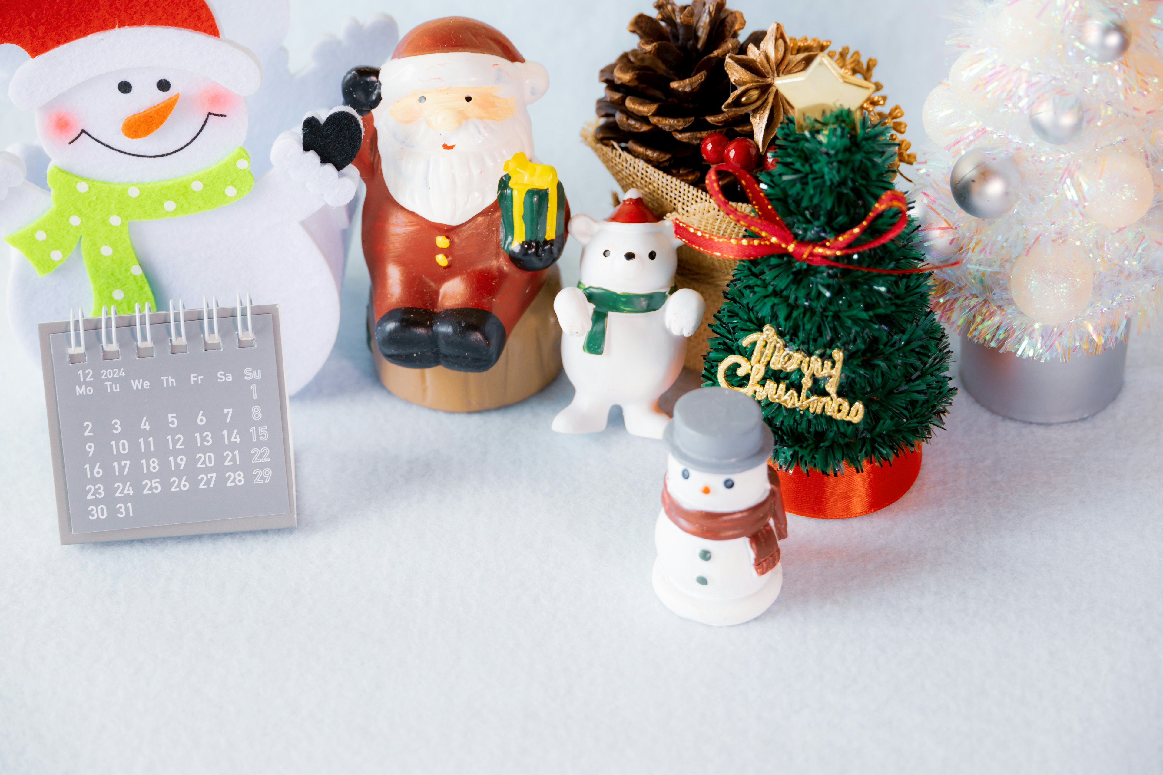 Christmas decorations on a table featuring Santa Claus, a snowman, a Christmas tree, and a calendar