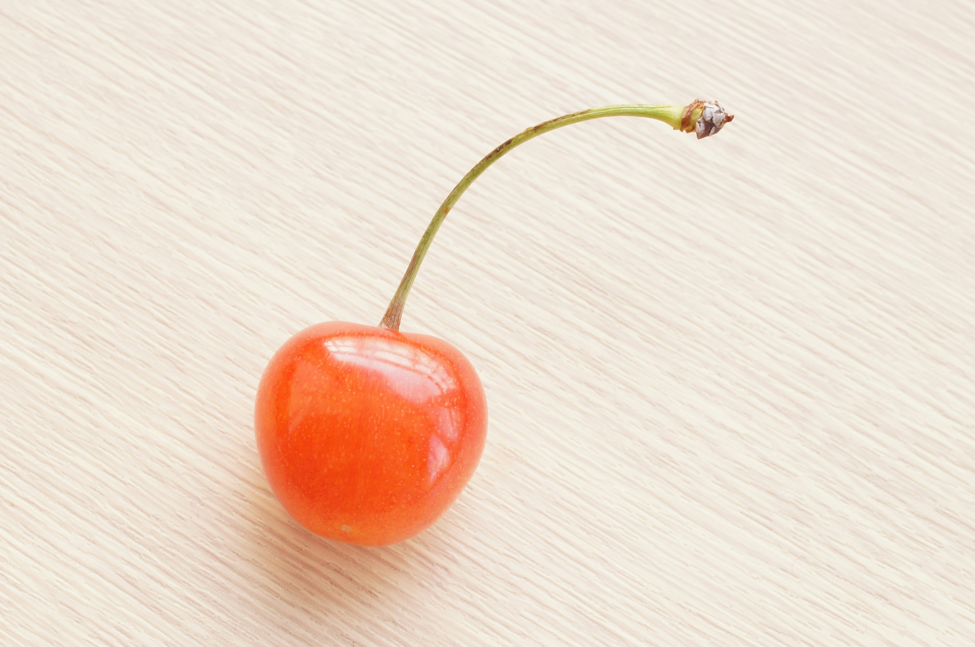 Une cerise orange vif reposant sur une table en bois