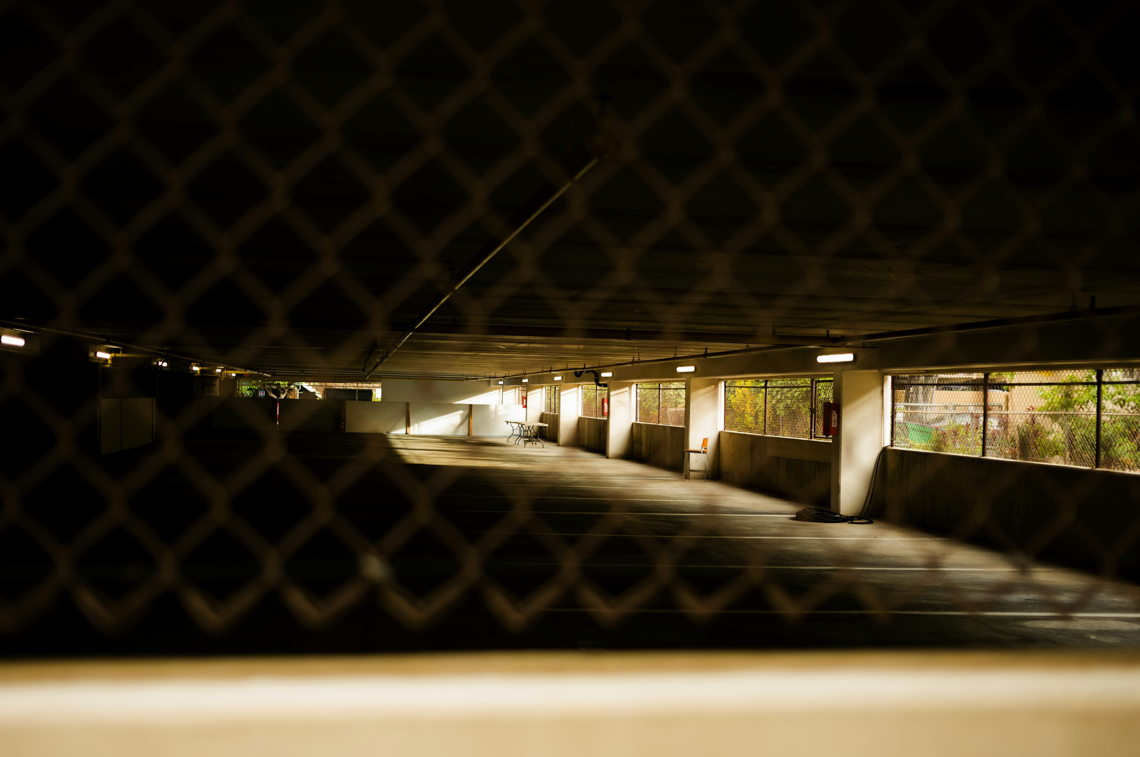 Vista di un garage sotterraneo poco illuminato attraverso una rete metallica