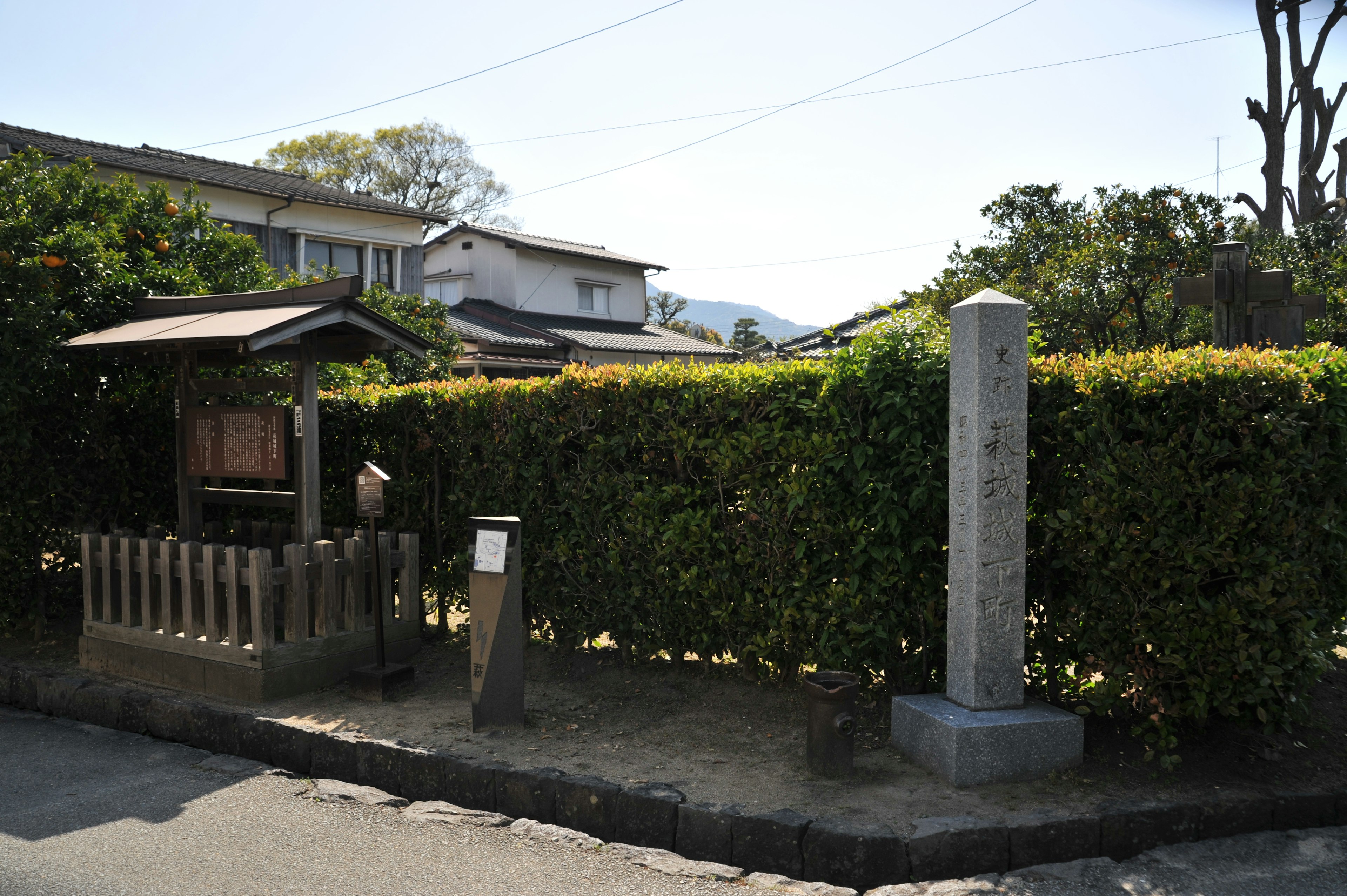 Landscape featuring a stone monument and a wooden signboard surrounded by lush greenery