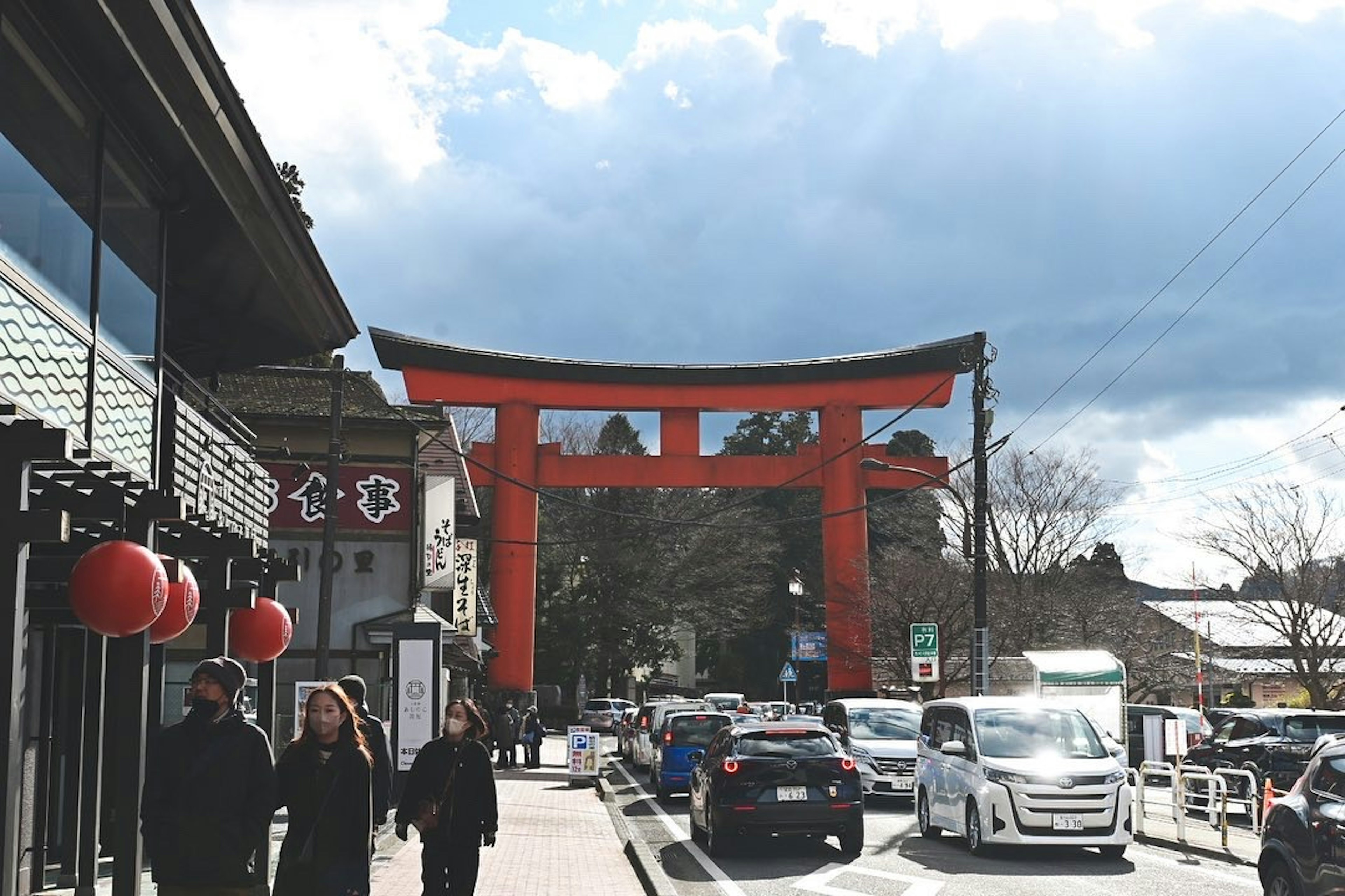 Cổng torii màu đỏ với cảnh đường phố mọi người đi bộ