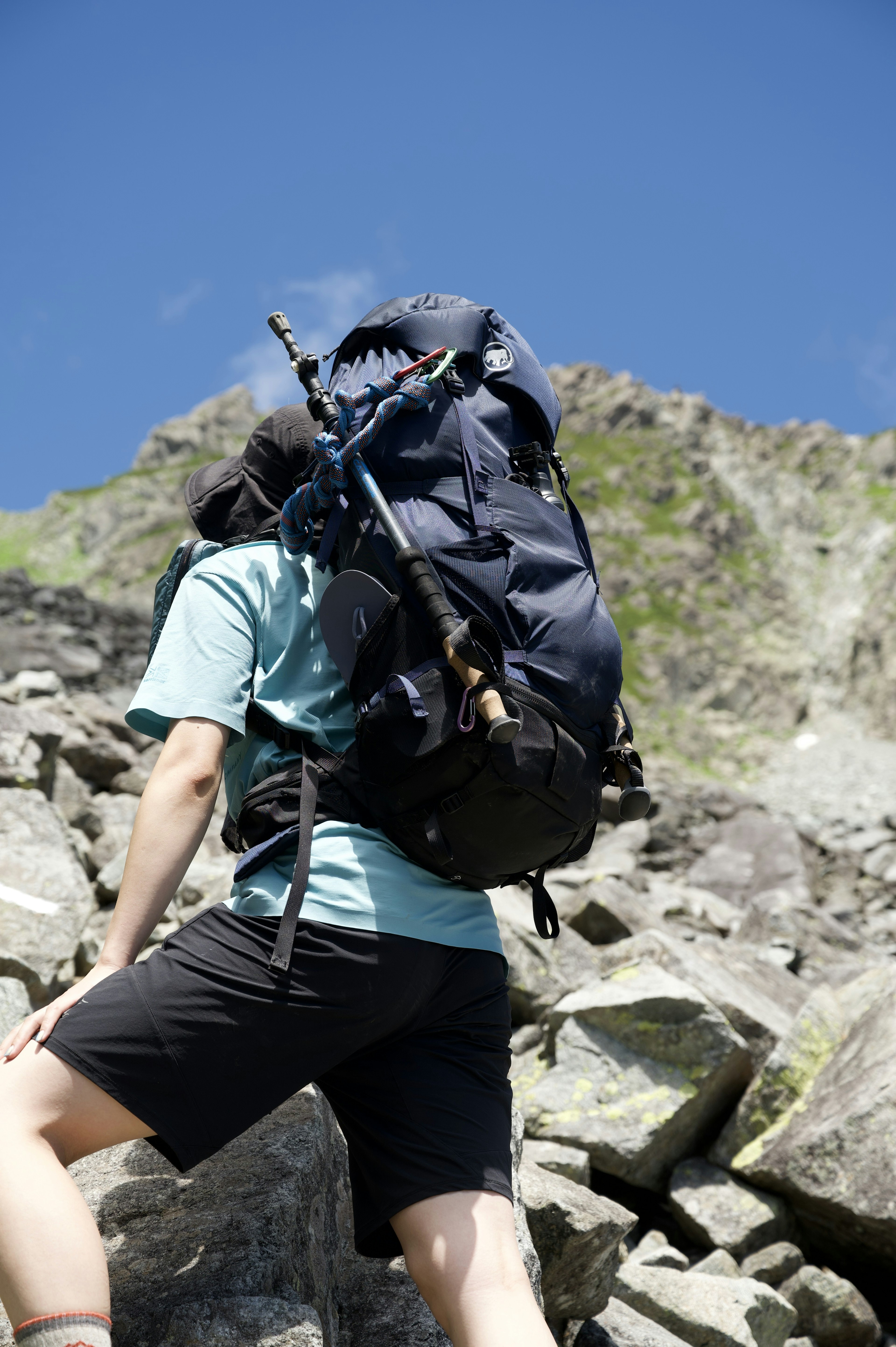 Person, die mit einem großen Rucksack in einem bergigen Gebiet Felsen erklimmt