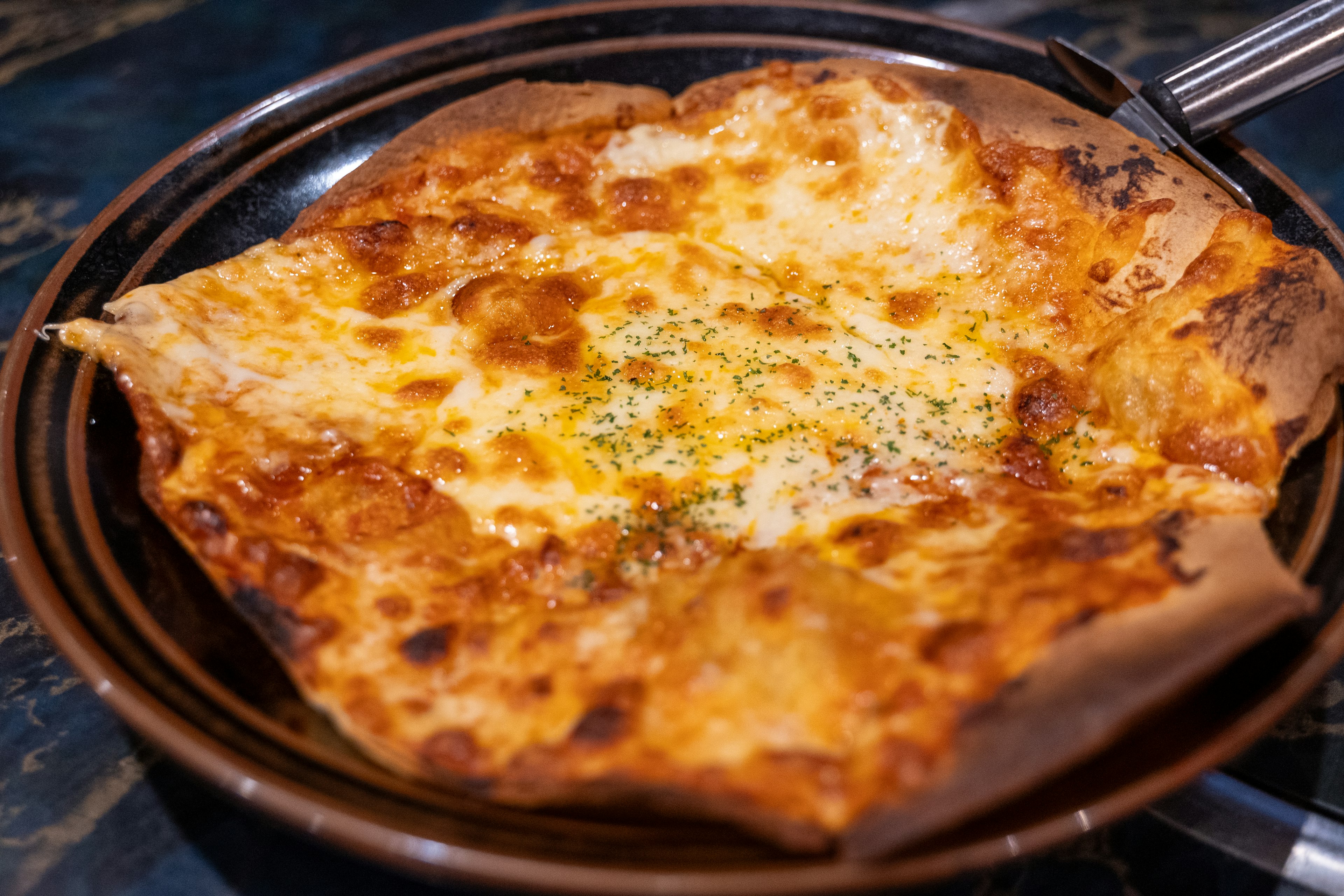 Pizza cotta con abbondante formaggio su un piatto nero