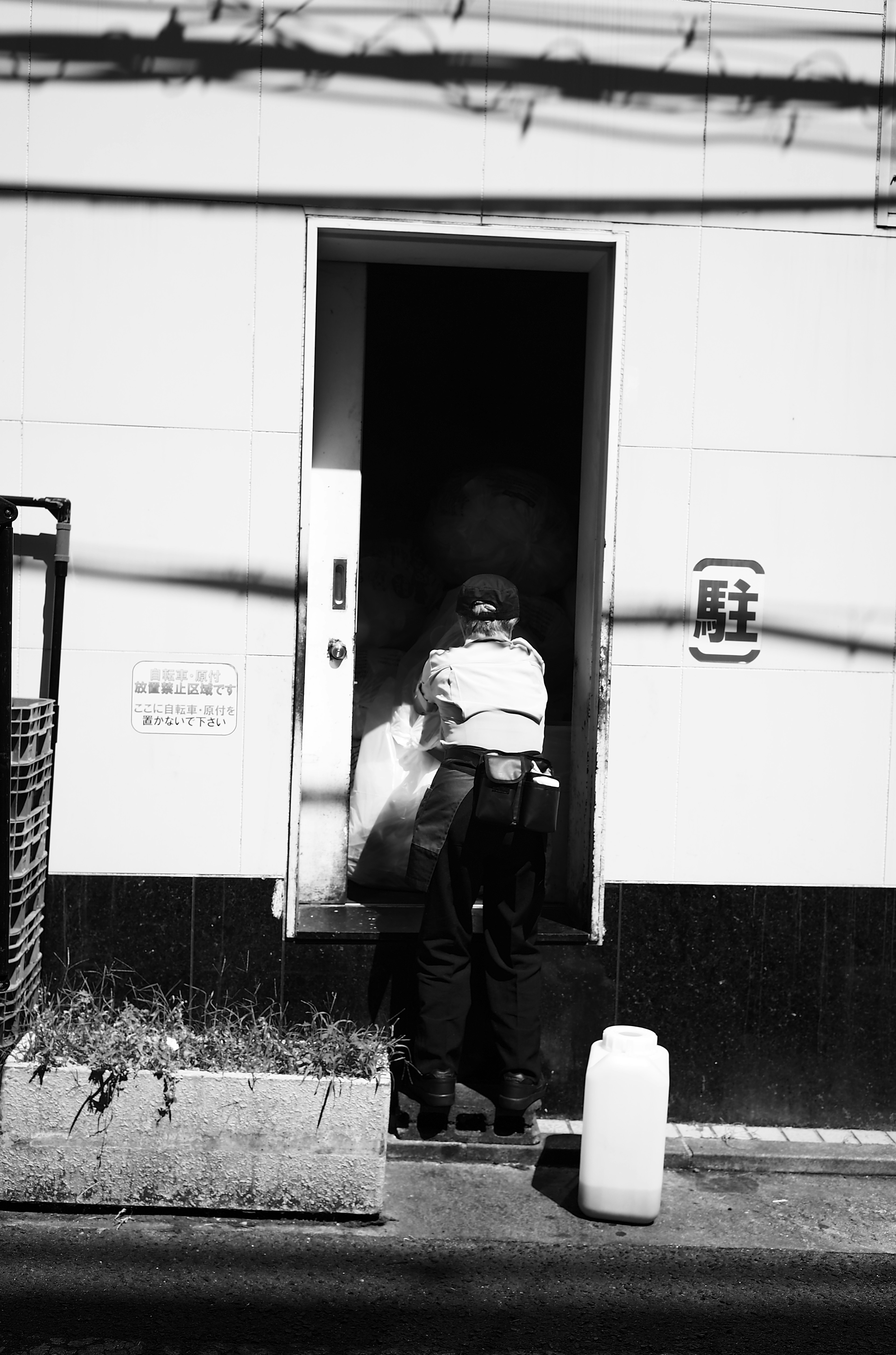 Une personne vue s'approchant d'une porte dans une photographie en noir et blanc