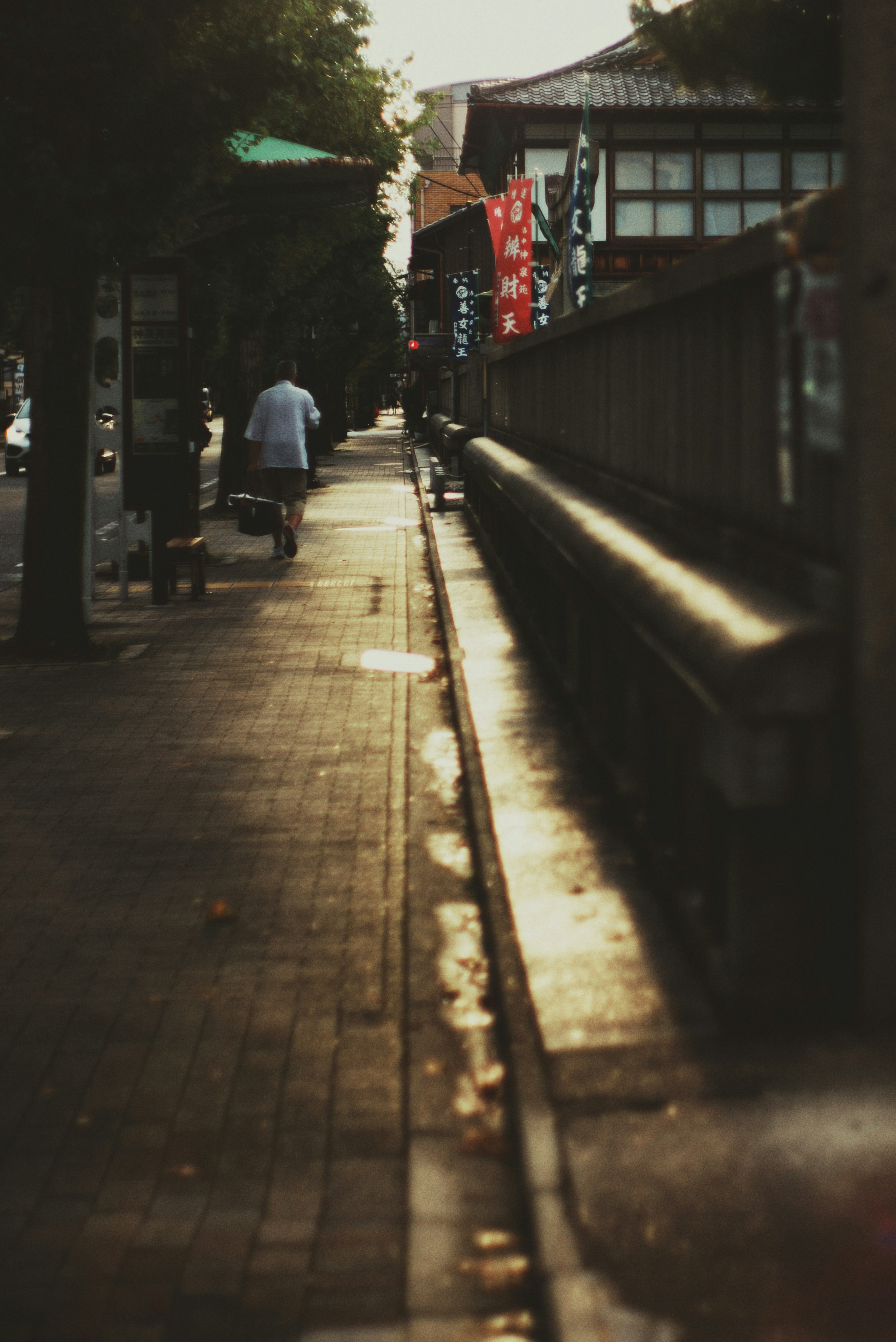 Sidewalk along a street at dusk with a silhouette of a person