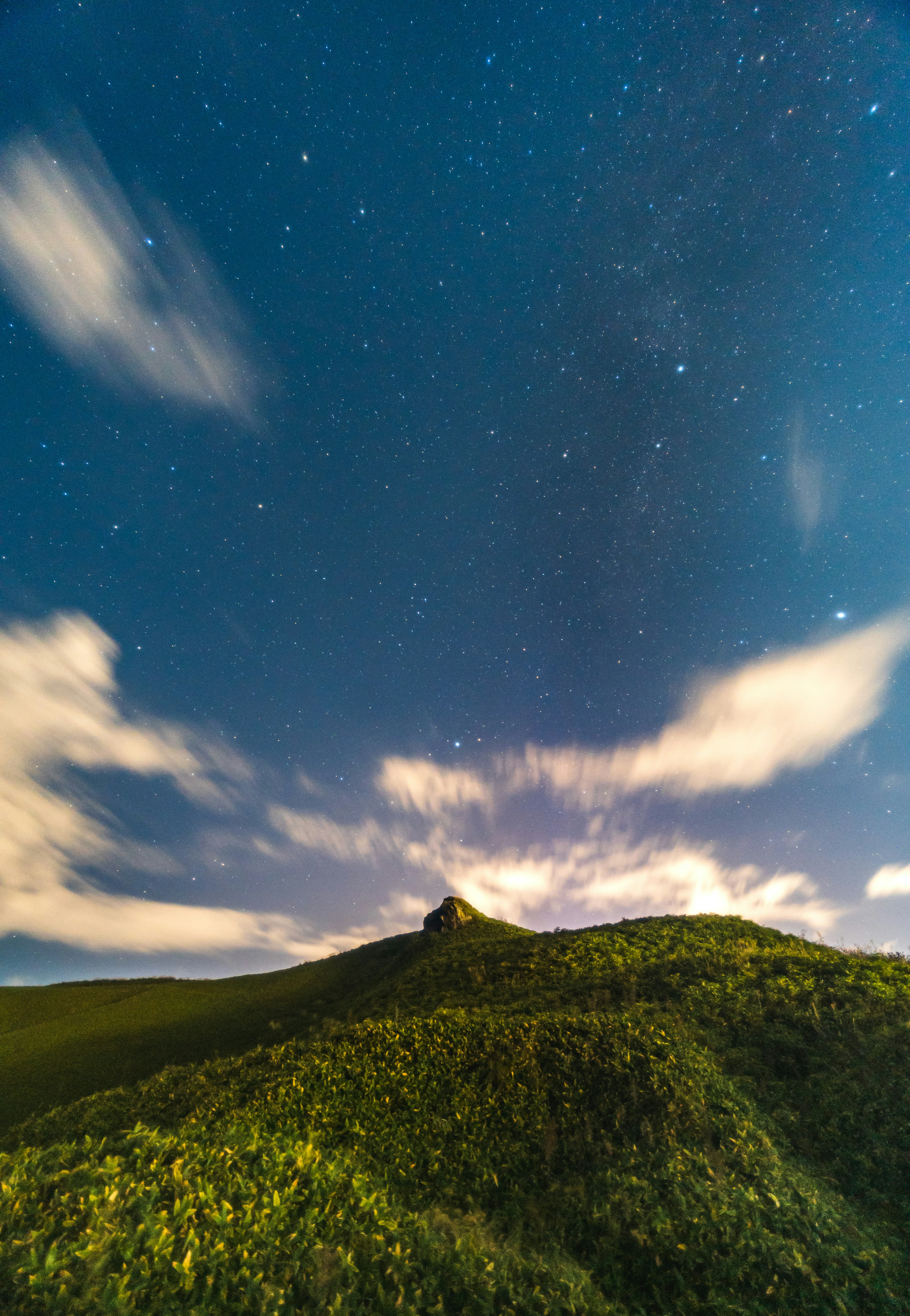 星空の下の緑の丘と雲