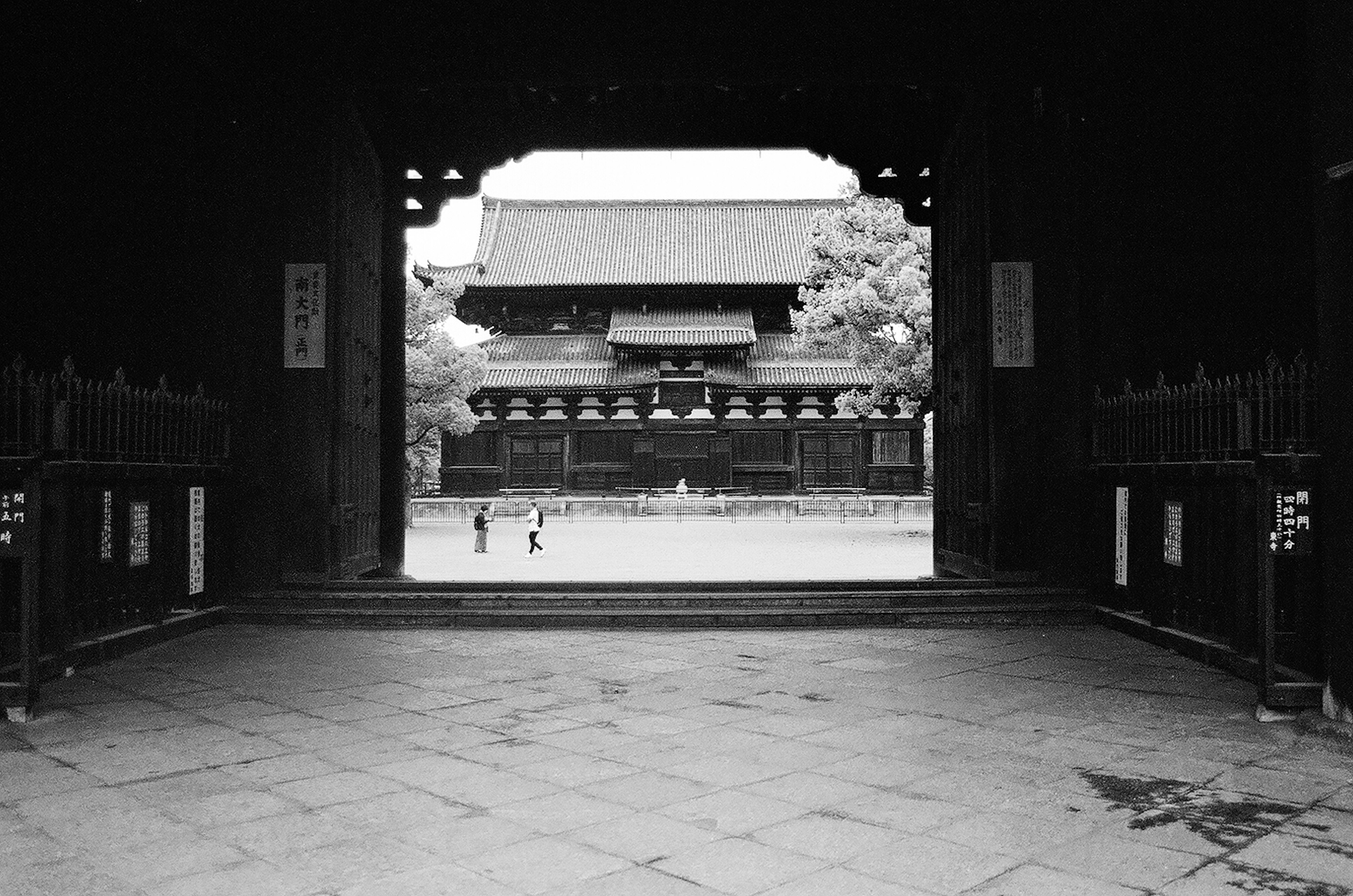 Bâtiment traditionnel et cour vus à travers une porte en noir et blanc