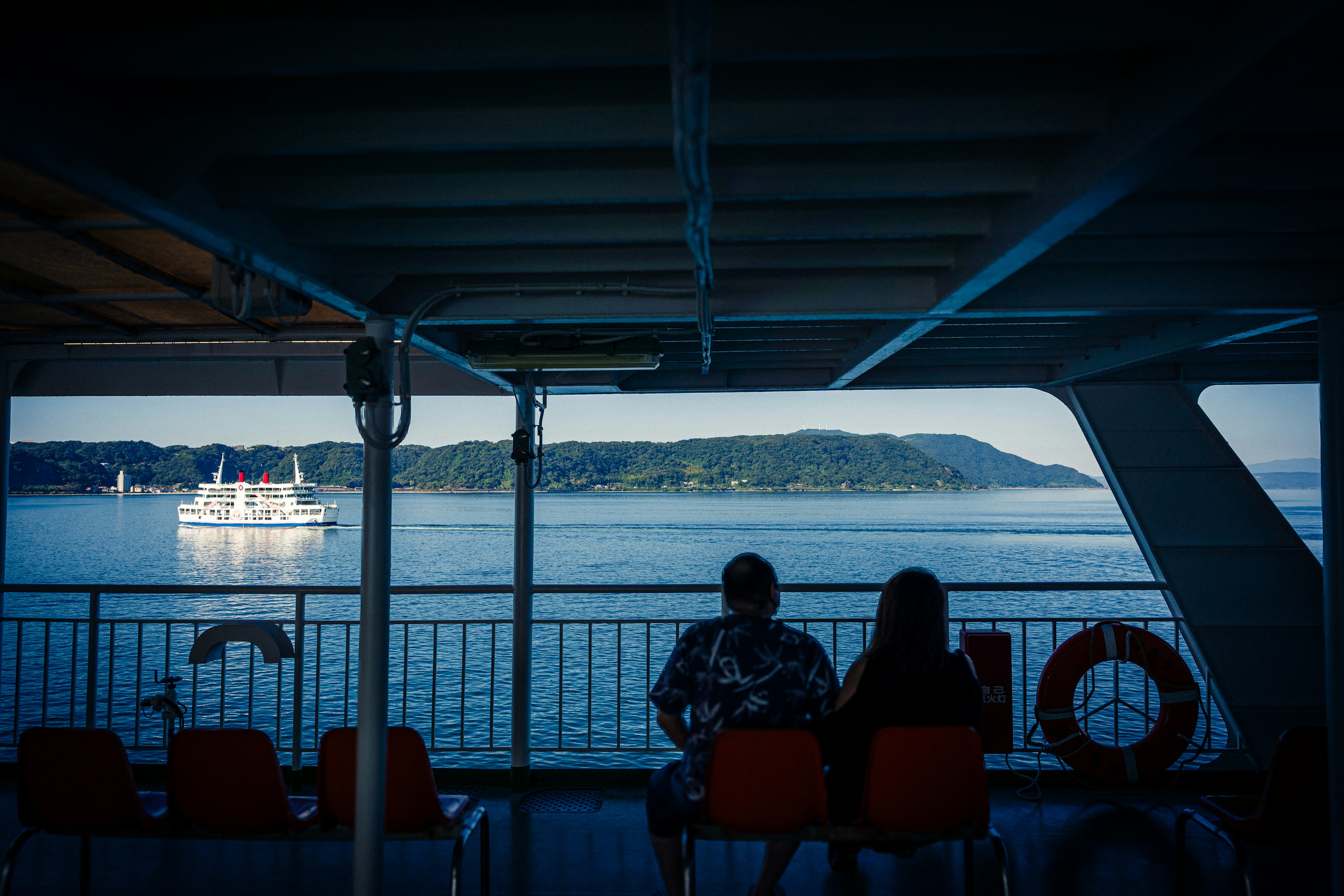 View of a serene sea landscape with two people on a ferry deck