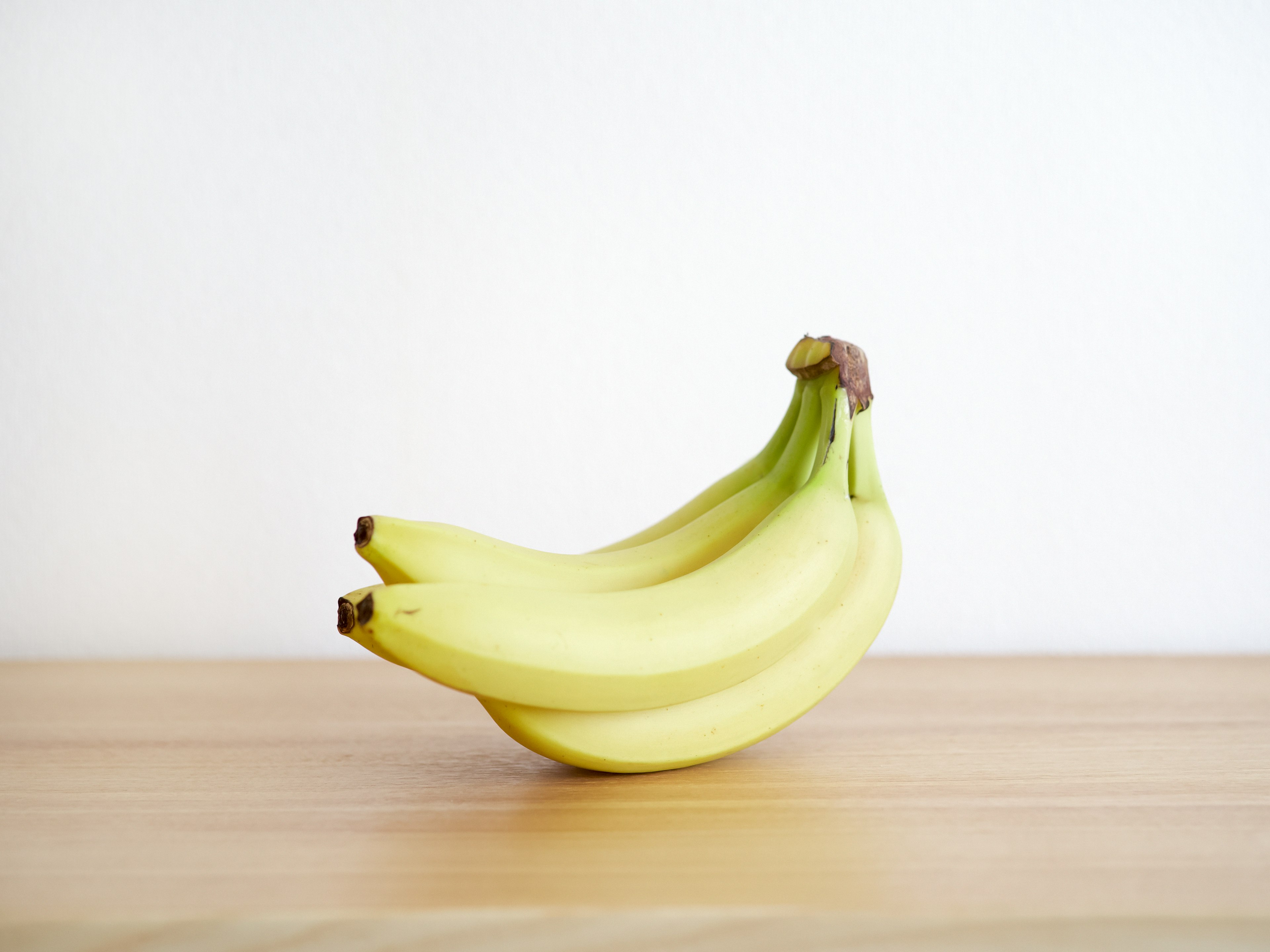 Three bananas resting on a wooden table