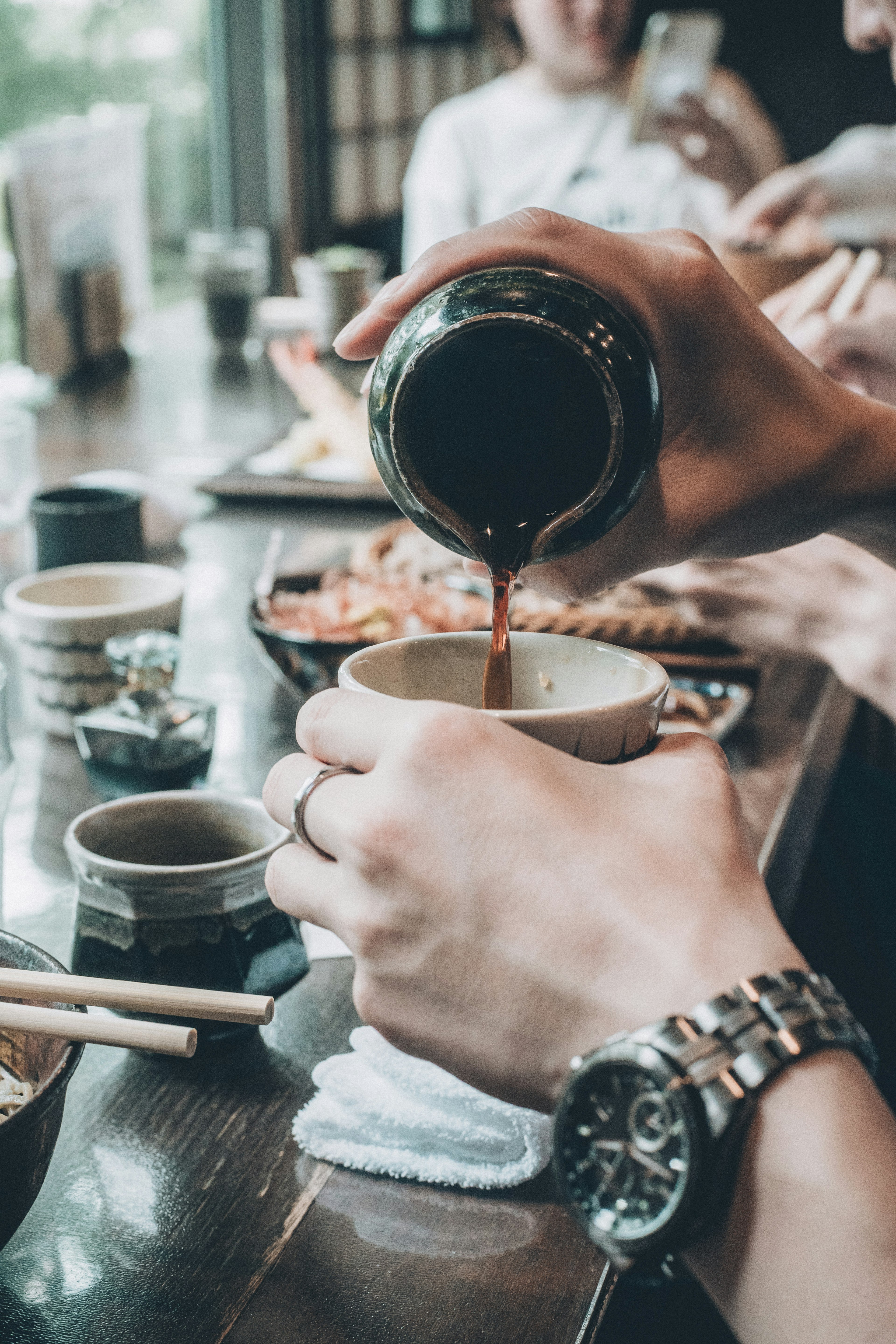 Hände gießen Sauce in eine Tasse in einer Essensszene