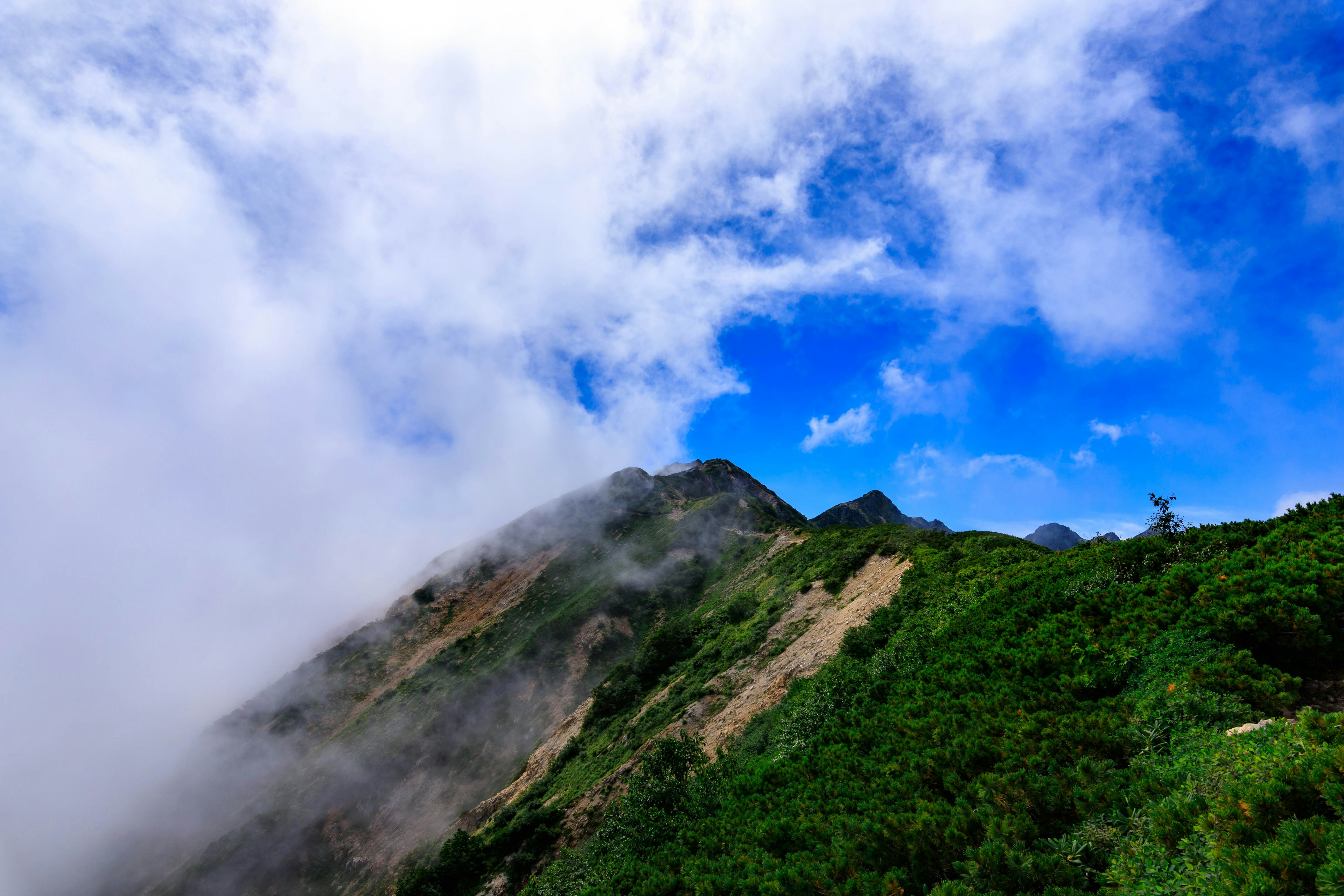 Paisaje montañoso exuberante con cielo azul y nubes