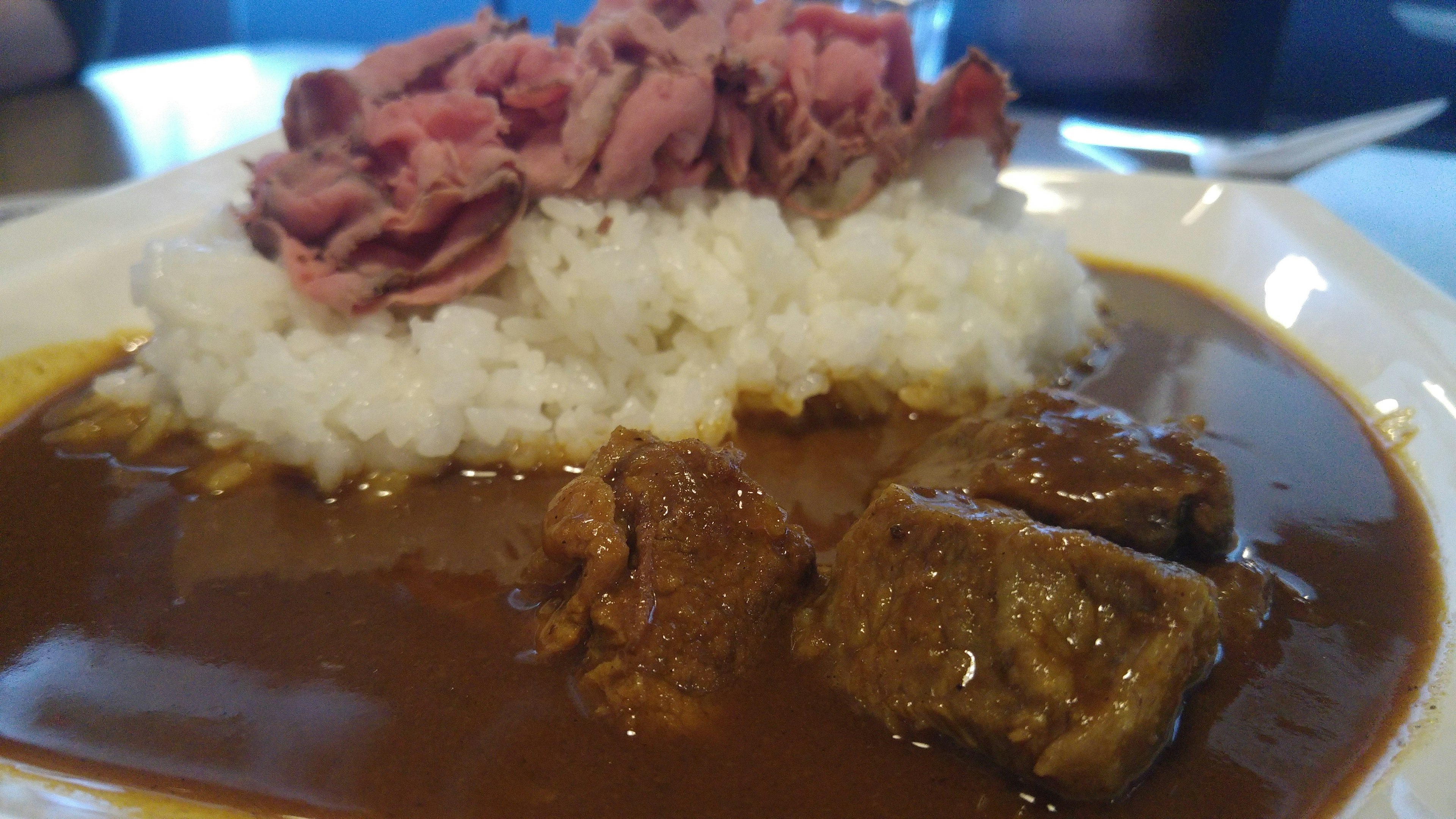 Curry servito su riso guarnito con fette di roast beef