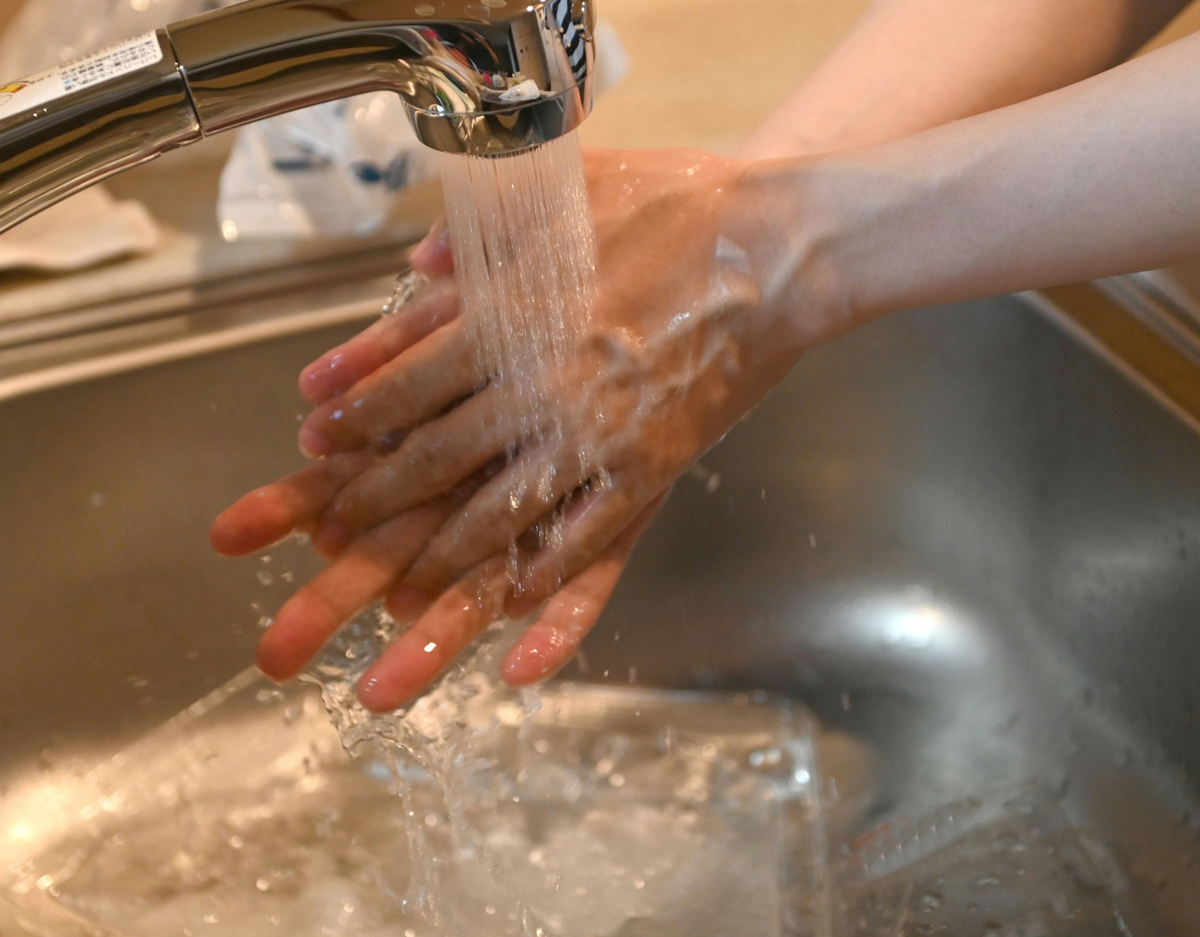 Hands being washed under a faucet with water flowing