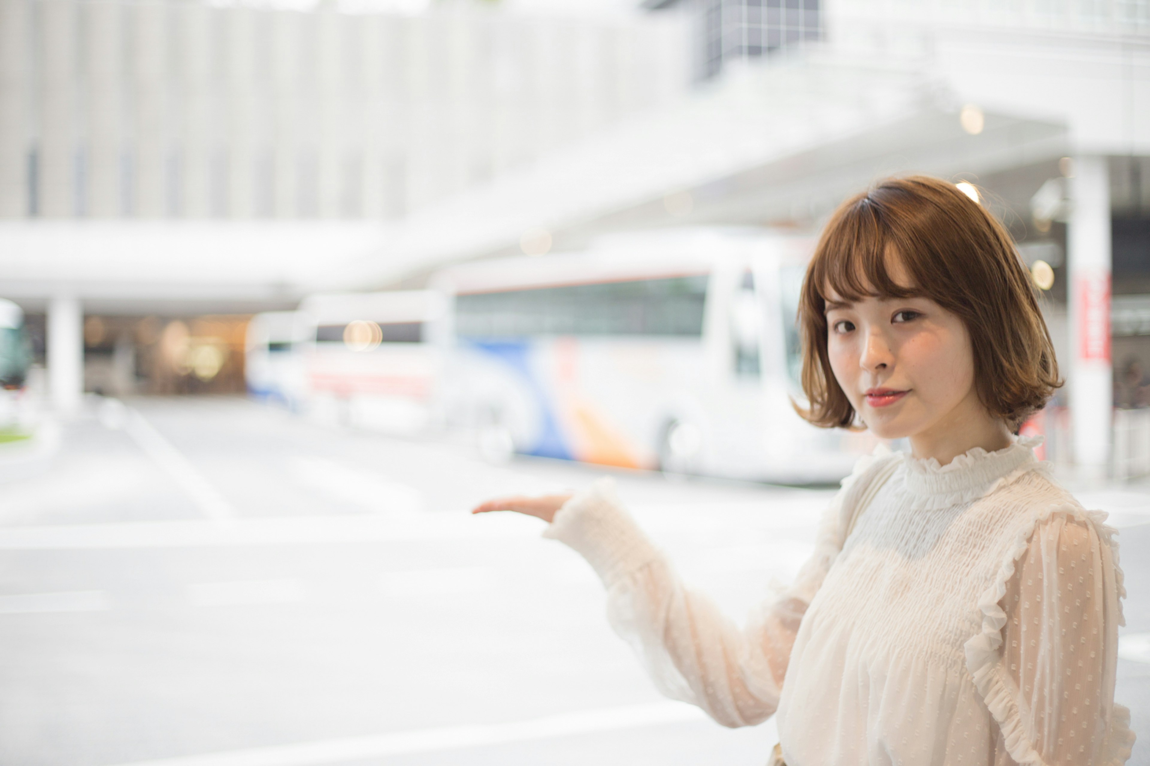 A woman gesturing with her hand in front of buses in the background