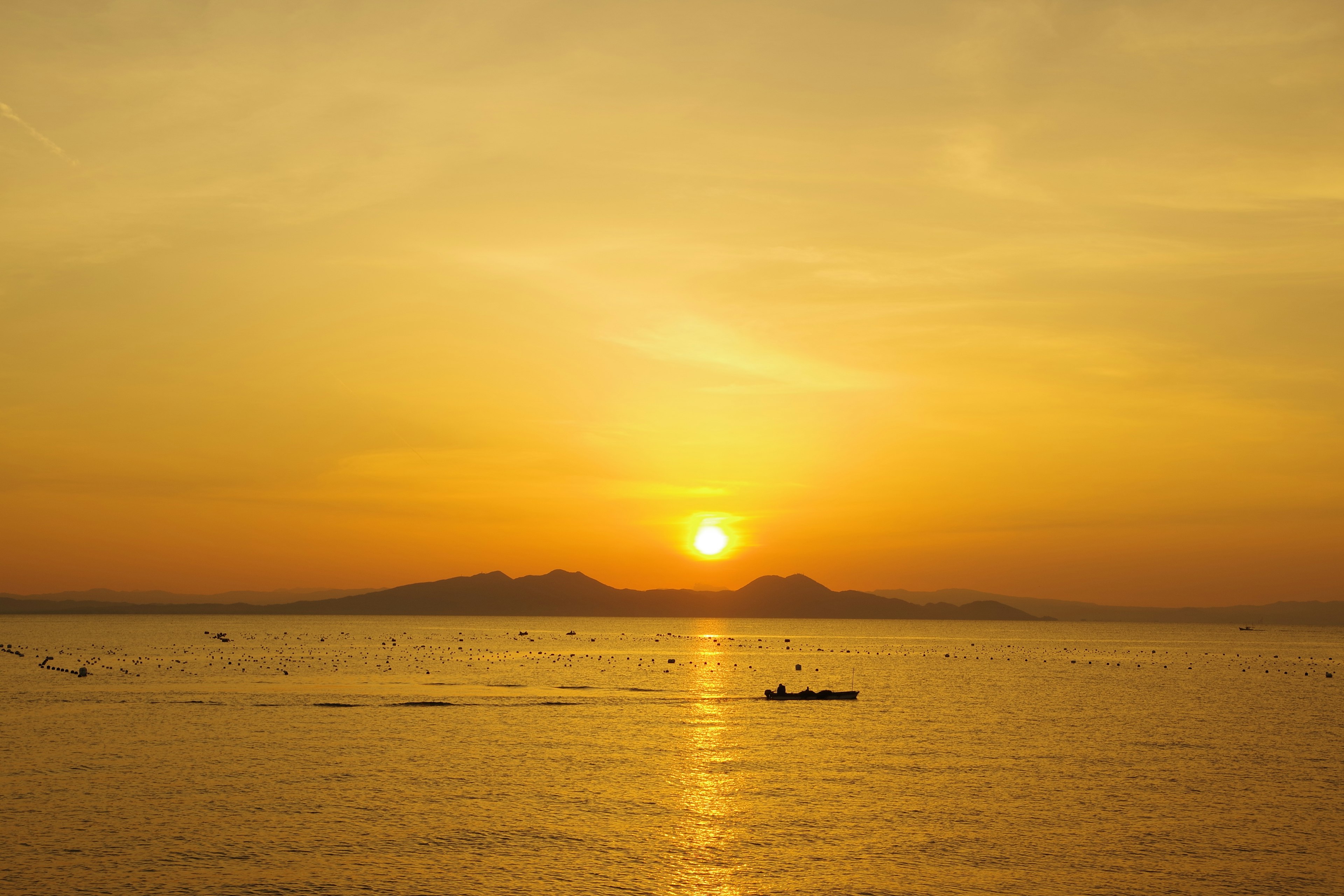 Hermosa vista del atardecer con siluetas de montañas y agua tranquila