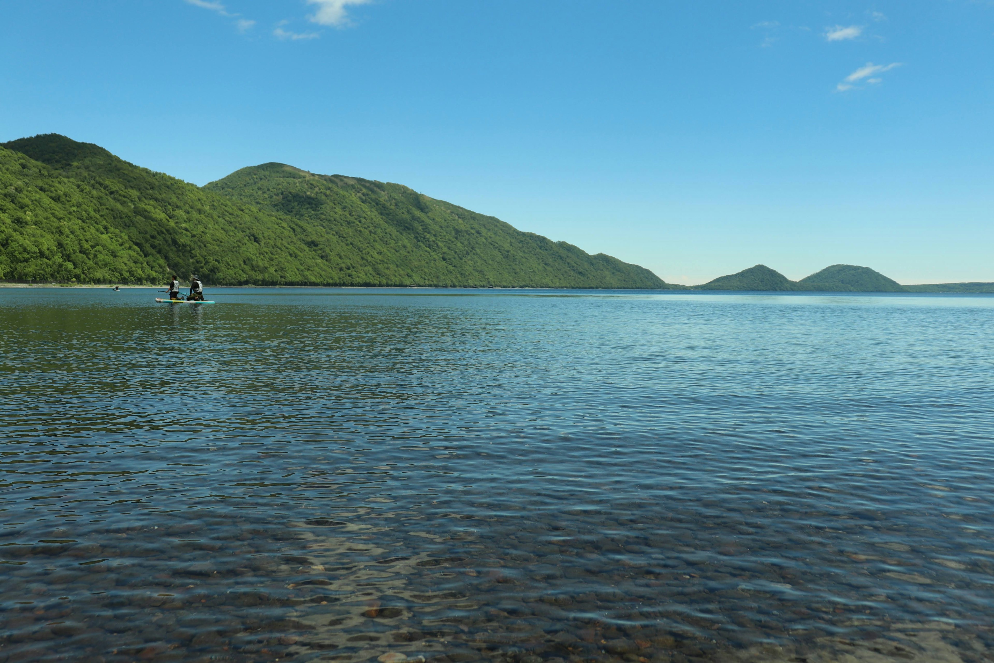 青い海と緑の山々が広がる風景に小舟が浮かぶ