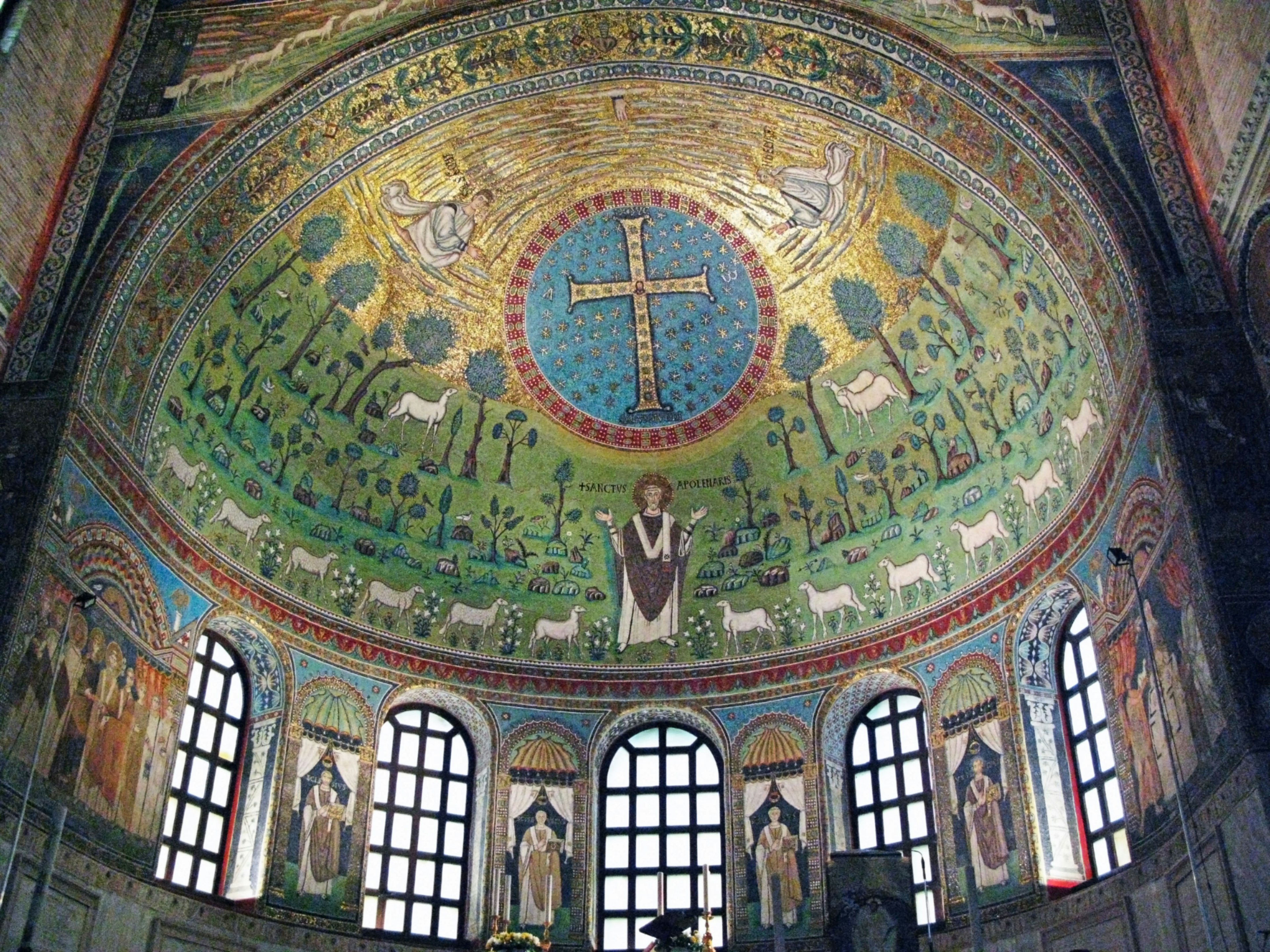 Interno di una chiesa con un bellissimo soffitto a mosaico con uno sfondo blu e verde che mostra una croce e pecore