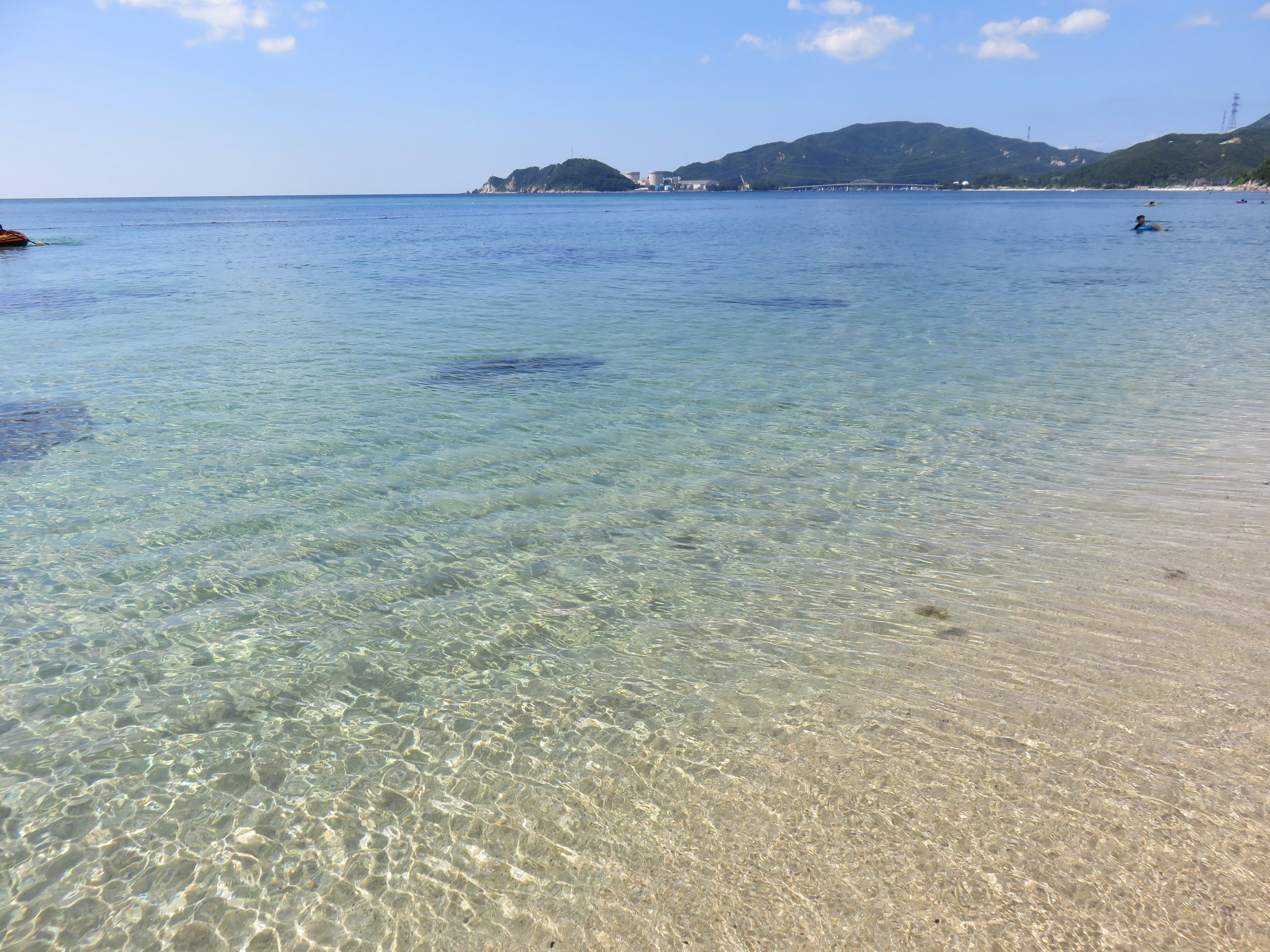 Laut jernih dengan pemandangan pantai tenang Langit biru dan bukit jauh