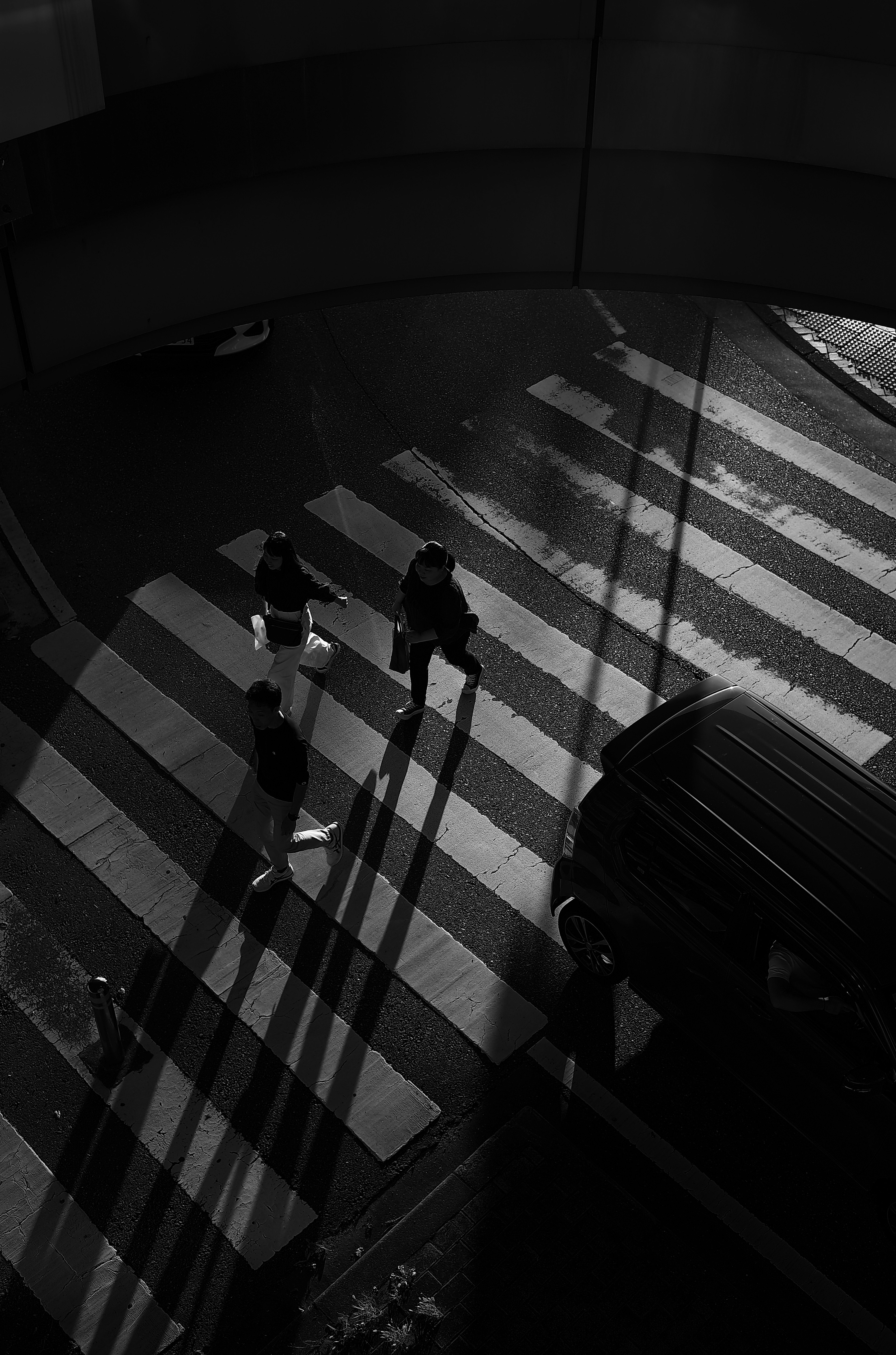 Shadows of pedestrians crossing a black and white striped crosswalk