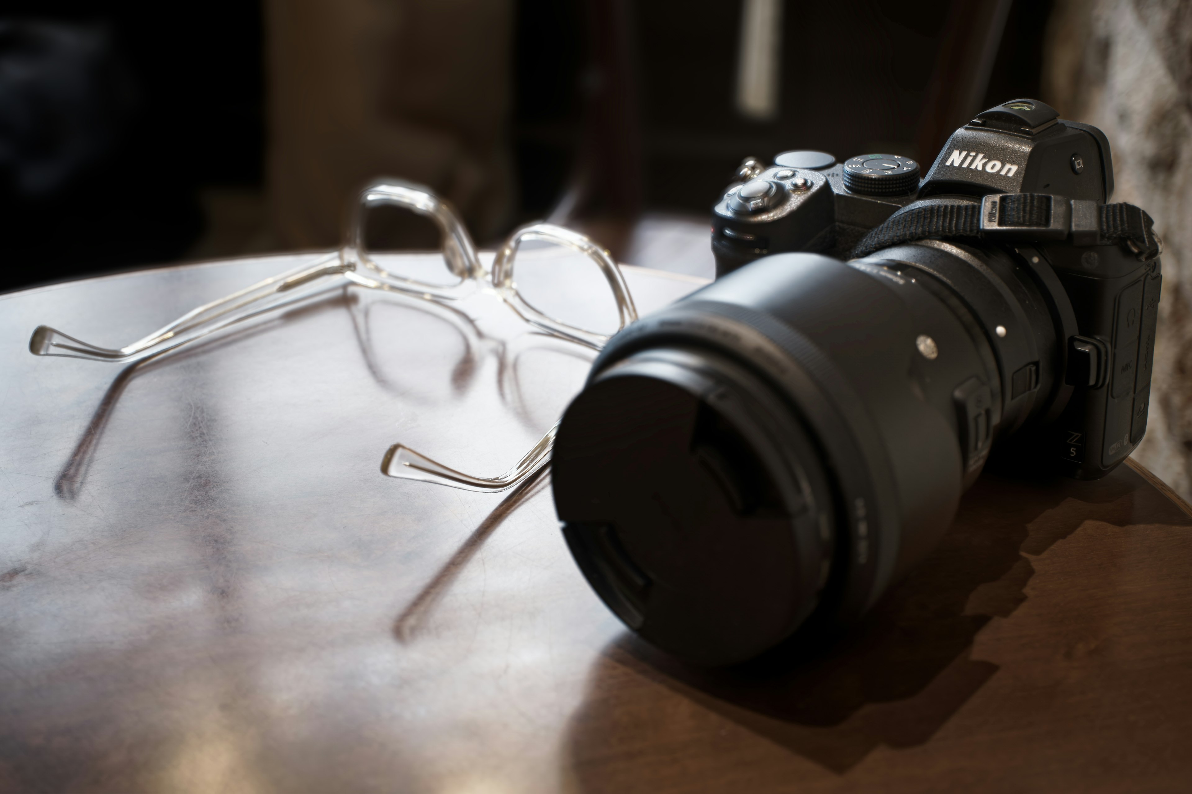 A camera and glasses resting on a wooden table