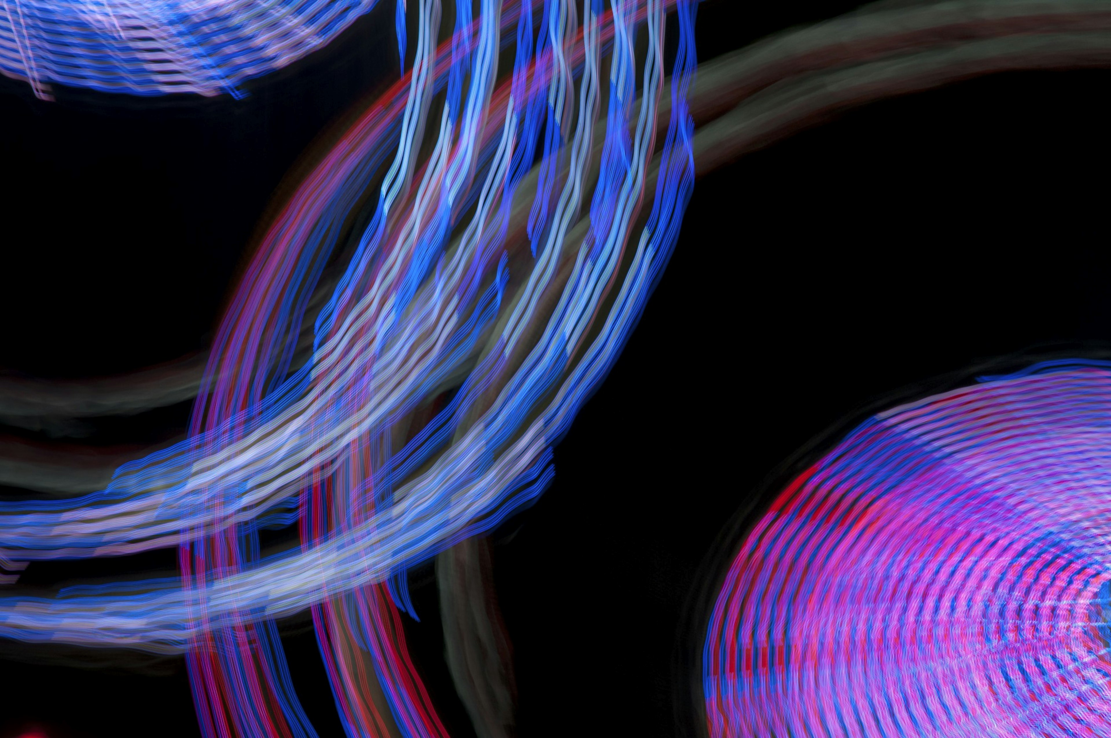 Abstract image featuring swirling blue and red lights against a black background