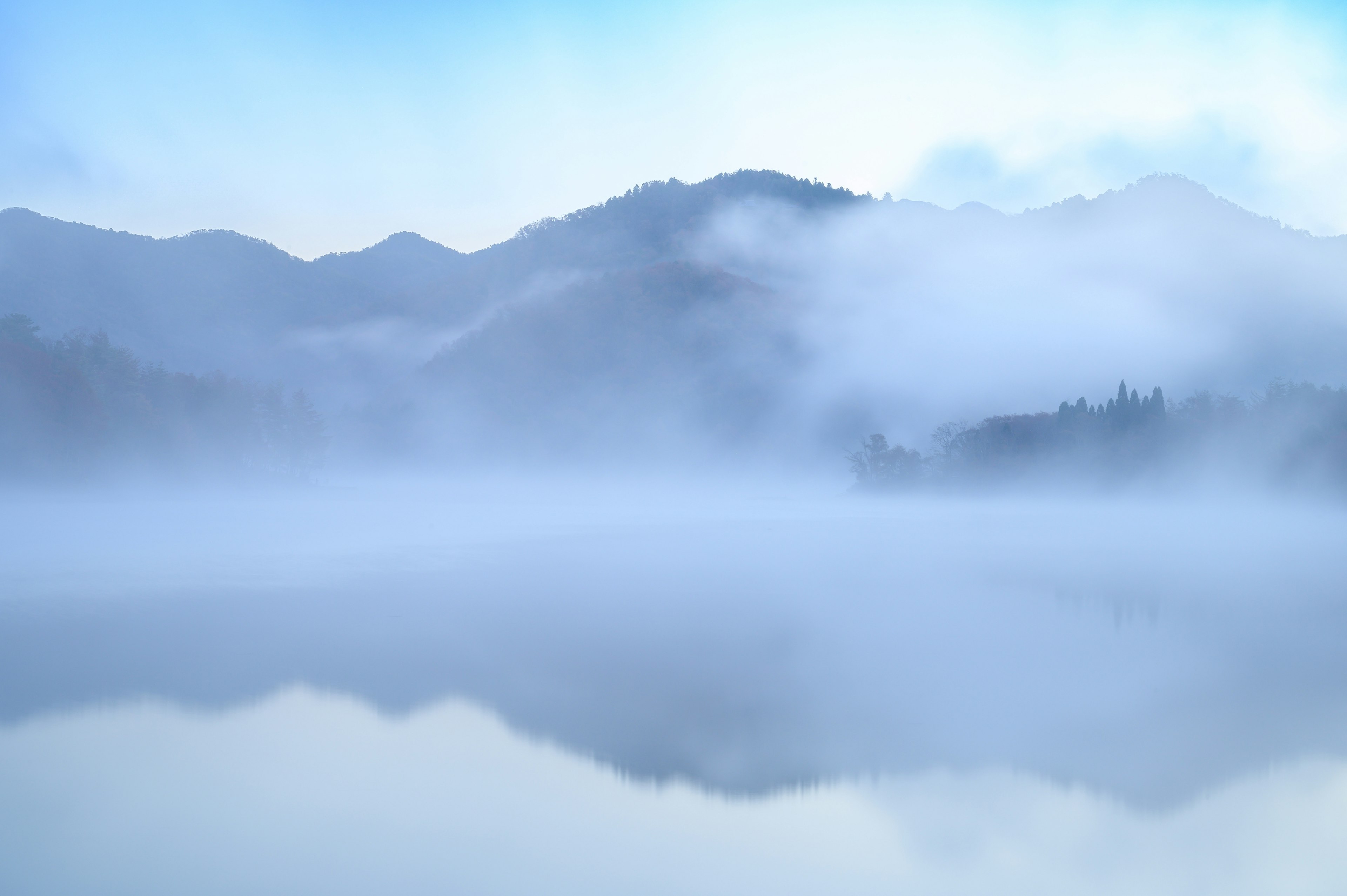 霧に包まれた山々と静かな湖の風景