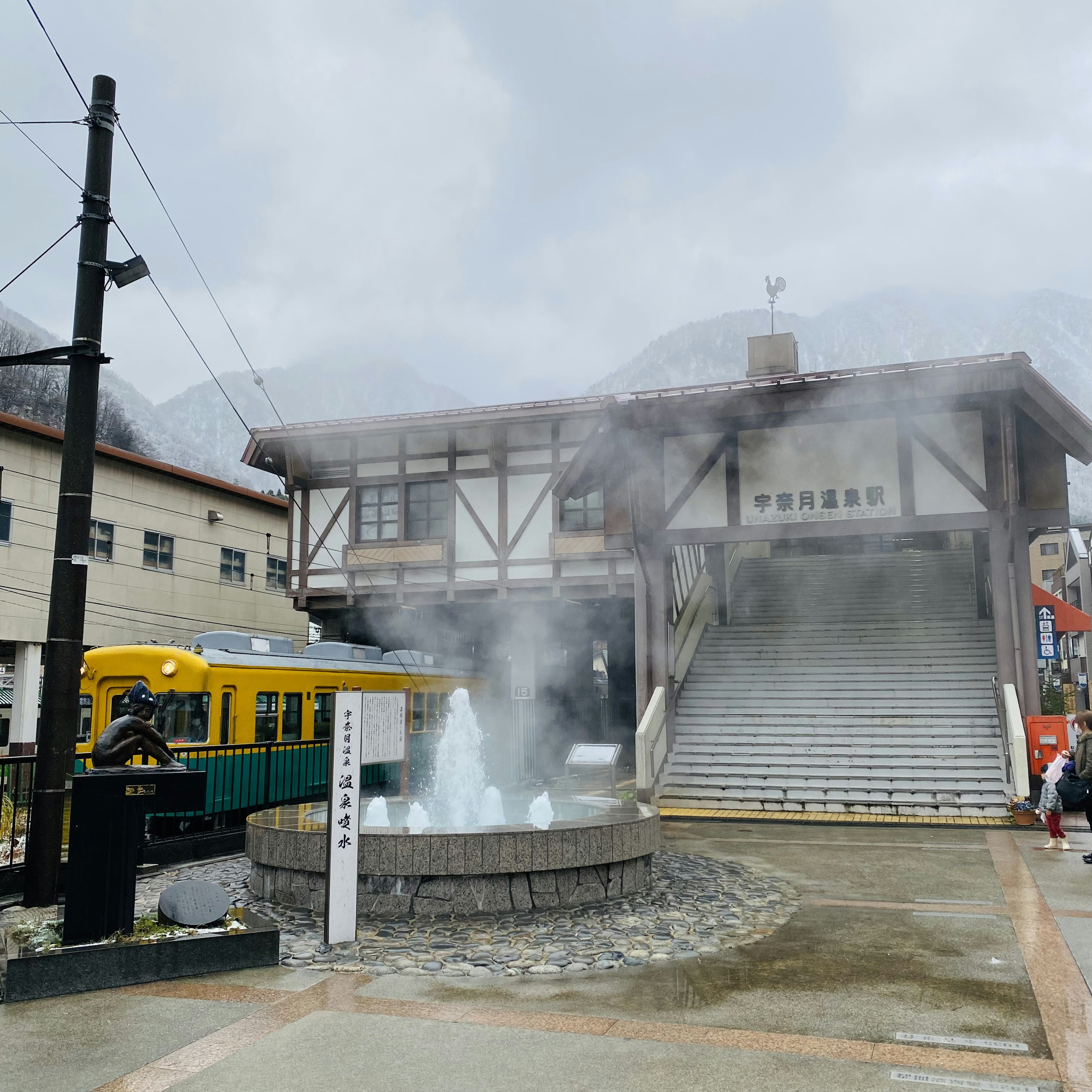 温泉街の駅舎と蒸気の出る噴水が特徴的な風景