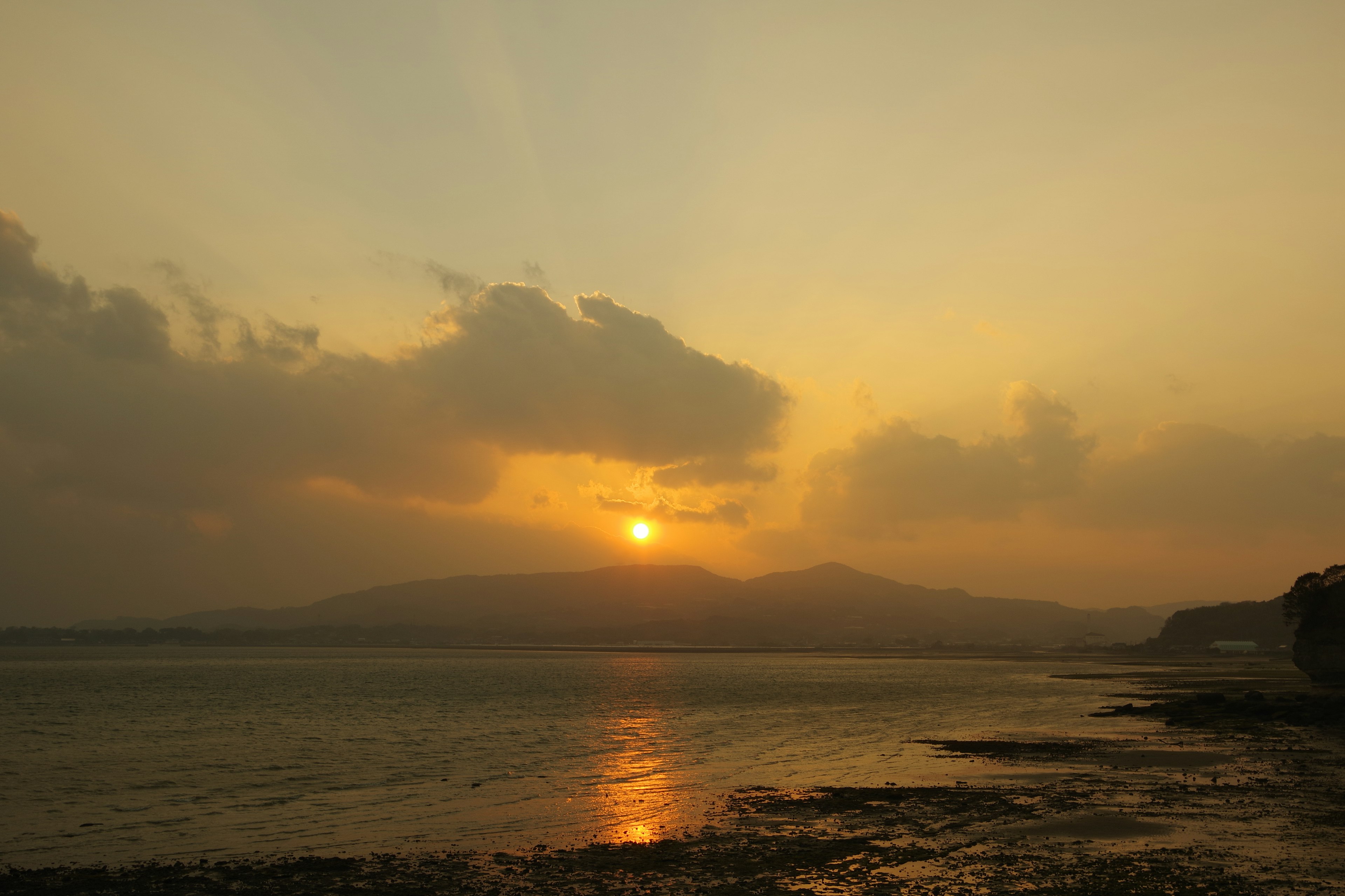 夕日が山々の間に沈む美しい海の風景