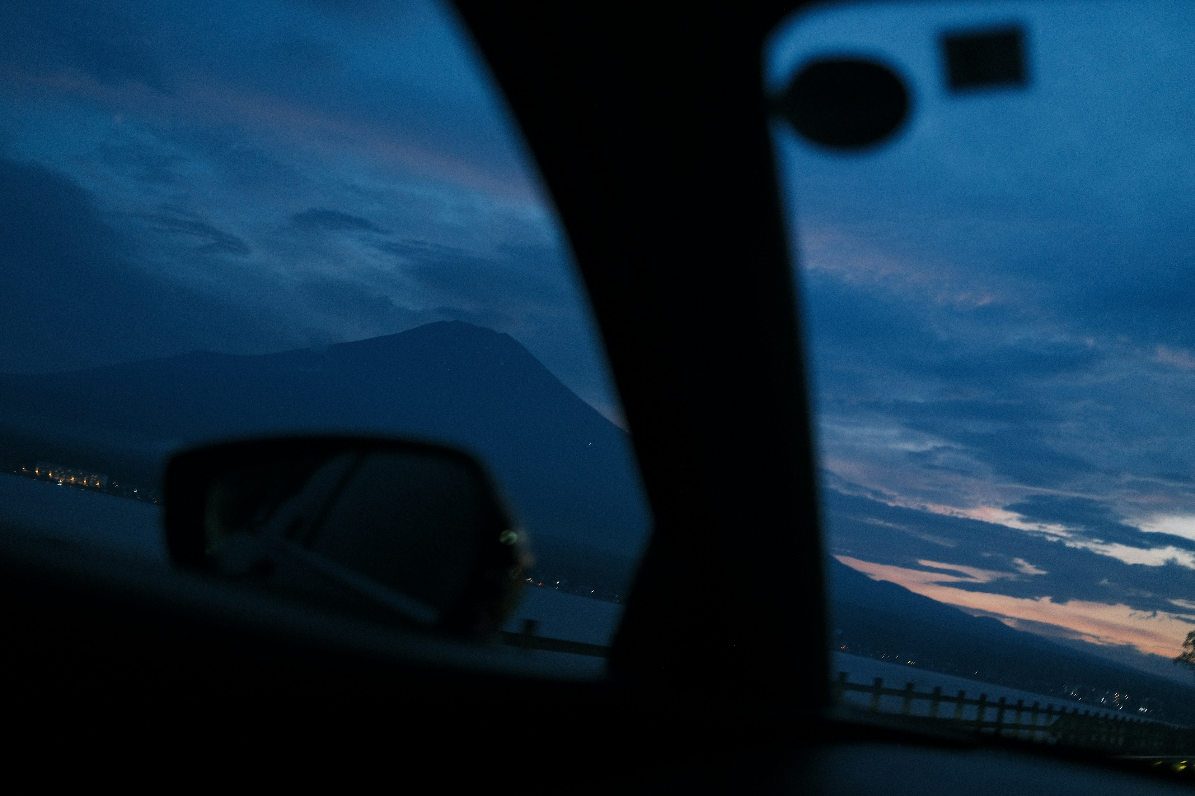 Pemandangan gunung dan langit senja melalui jendela mobil