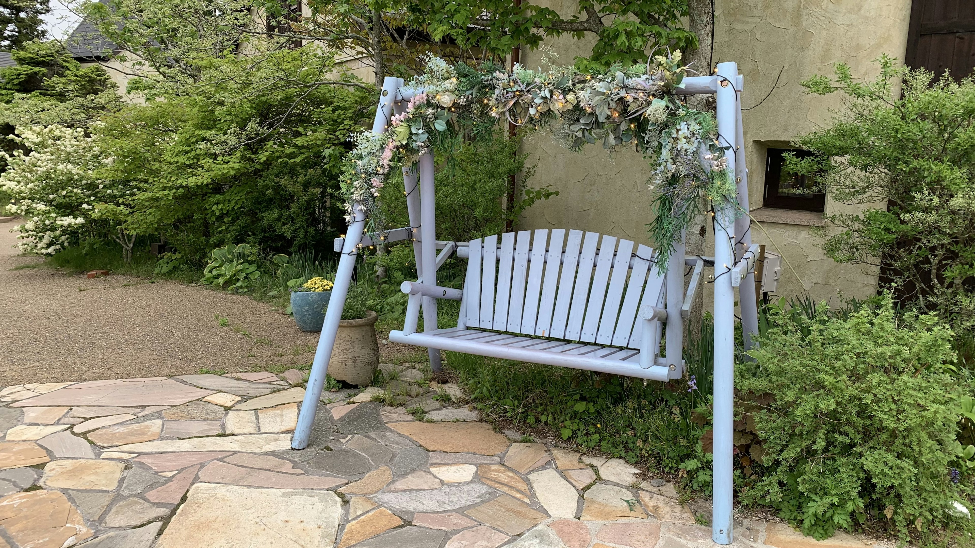 Un columpio azul decorado con flores en un jardín