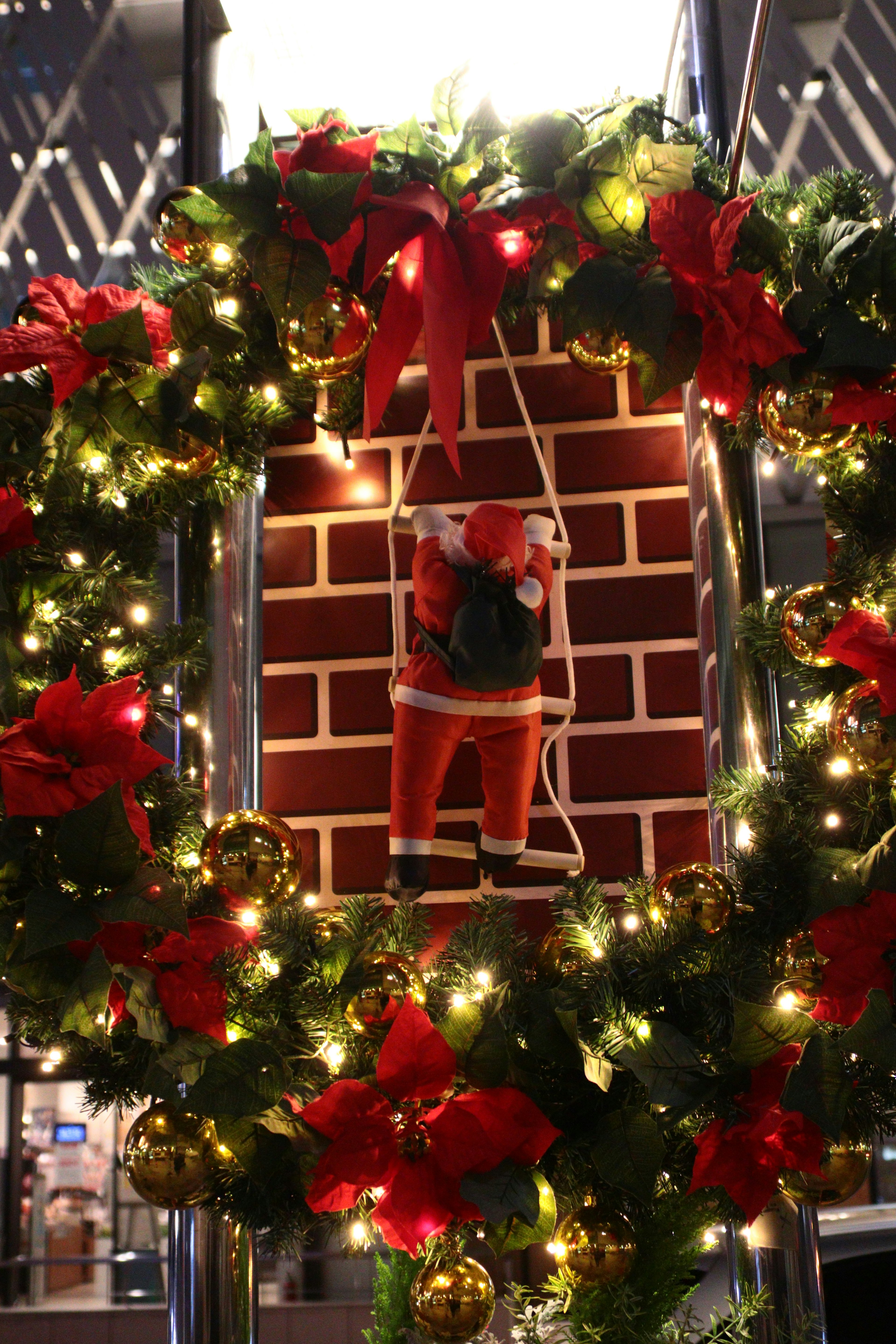 Weihnachtskranz mit Santa, der von einem Kamin heruntersteigt, umgeben von Lichtern