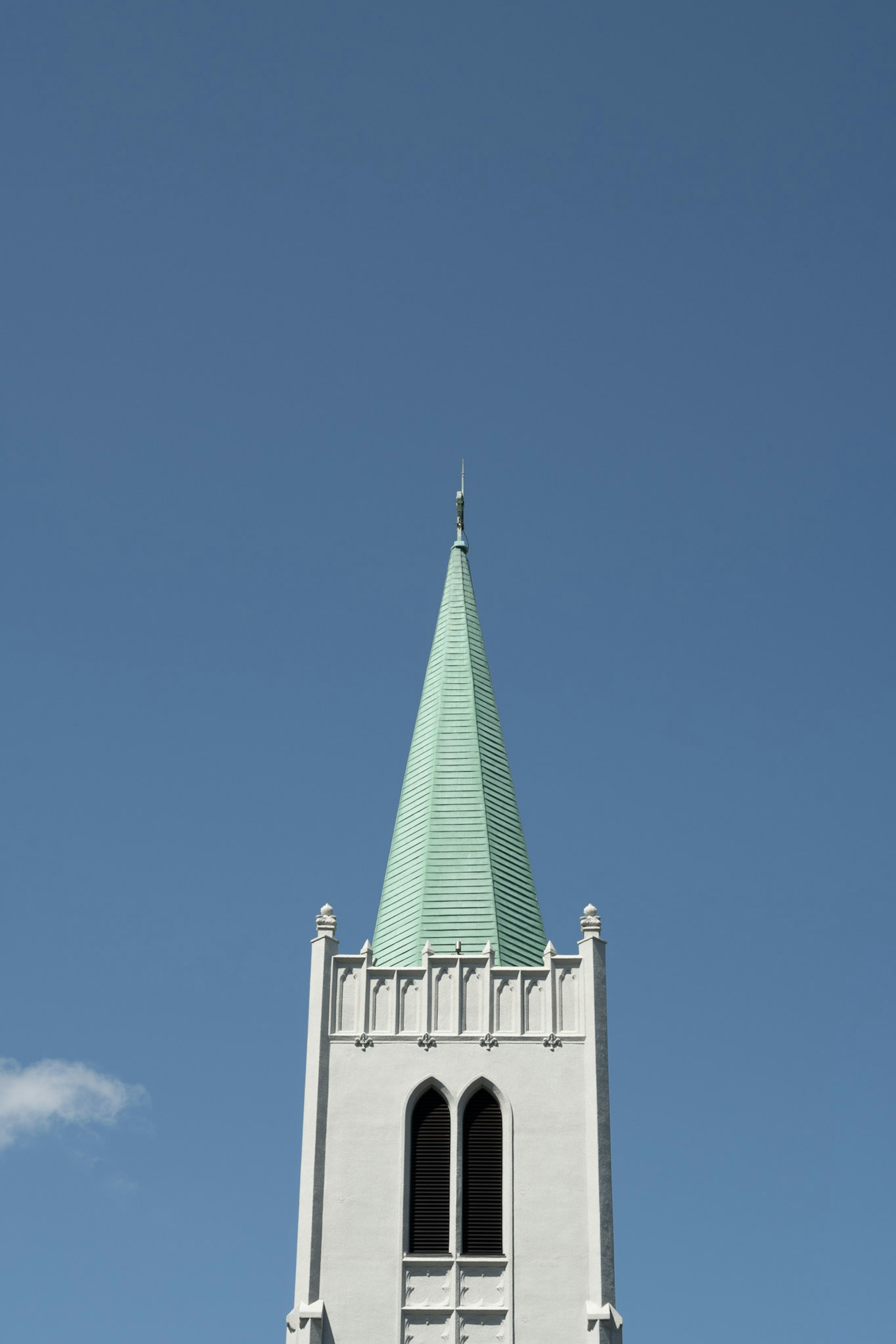 Torre de iglesia con una aguja verde contra un cielo azul