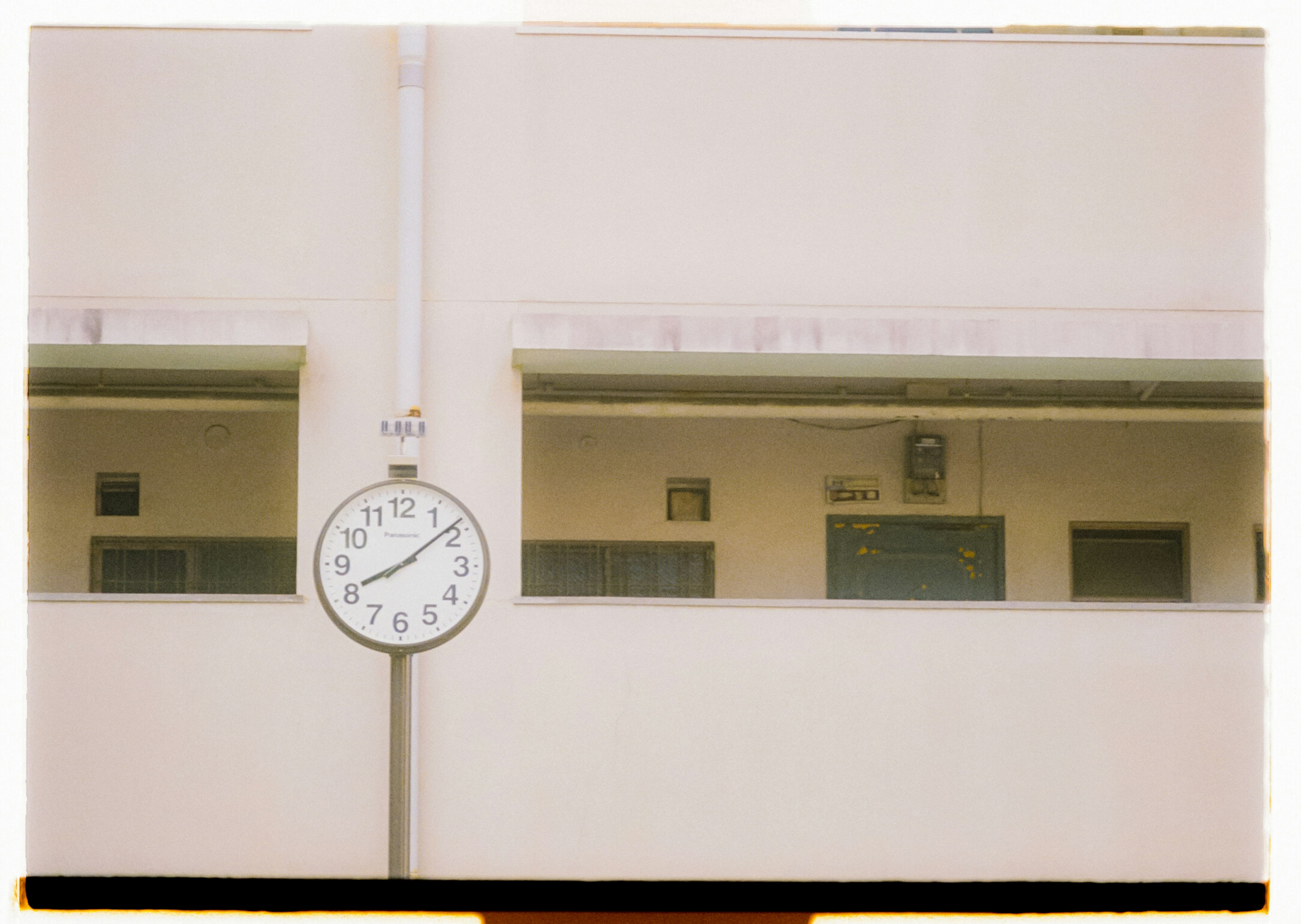 Grand horloge montée sur un mur blanc avec des fenêtres