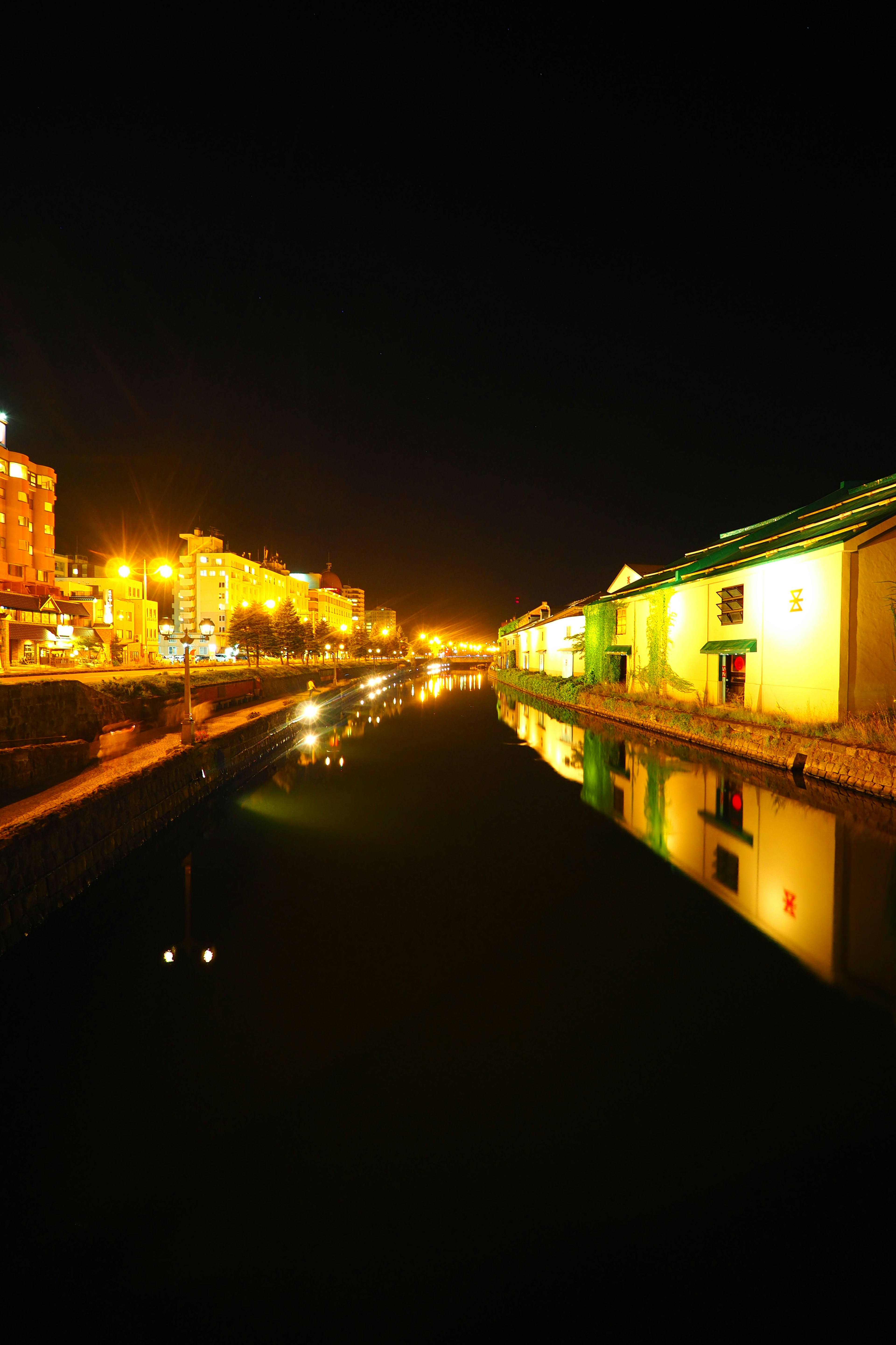 Vue nocturne d'un canal reflétant des lumières et des bâtiments