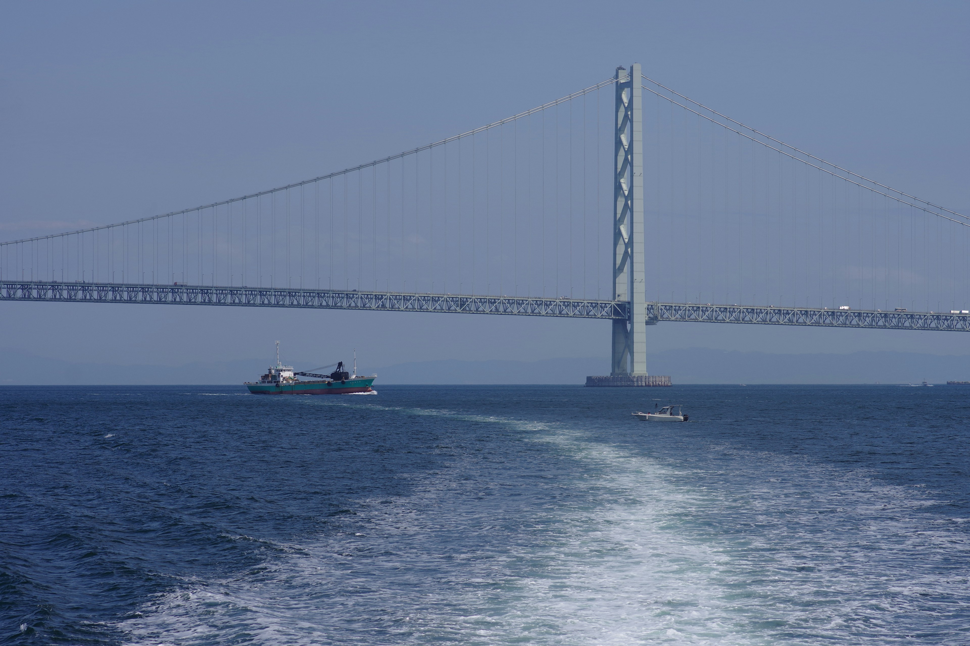 Una vista de un barco navegando en aguas azules con un puente al fondo