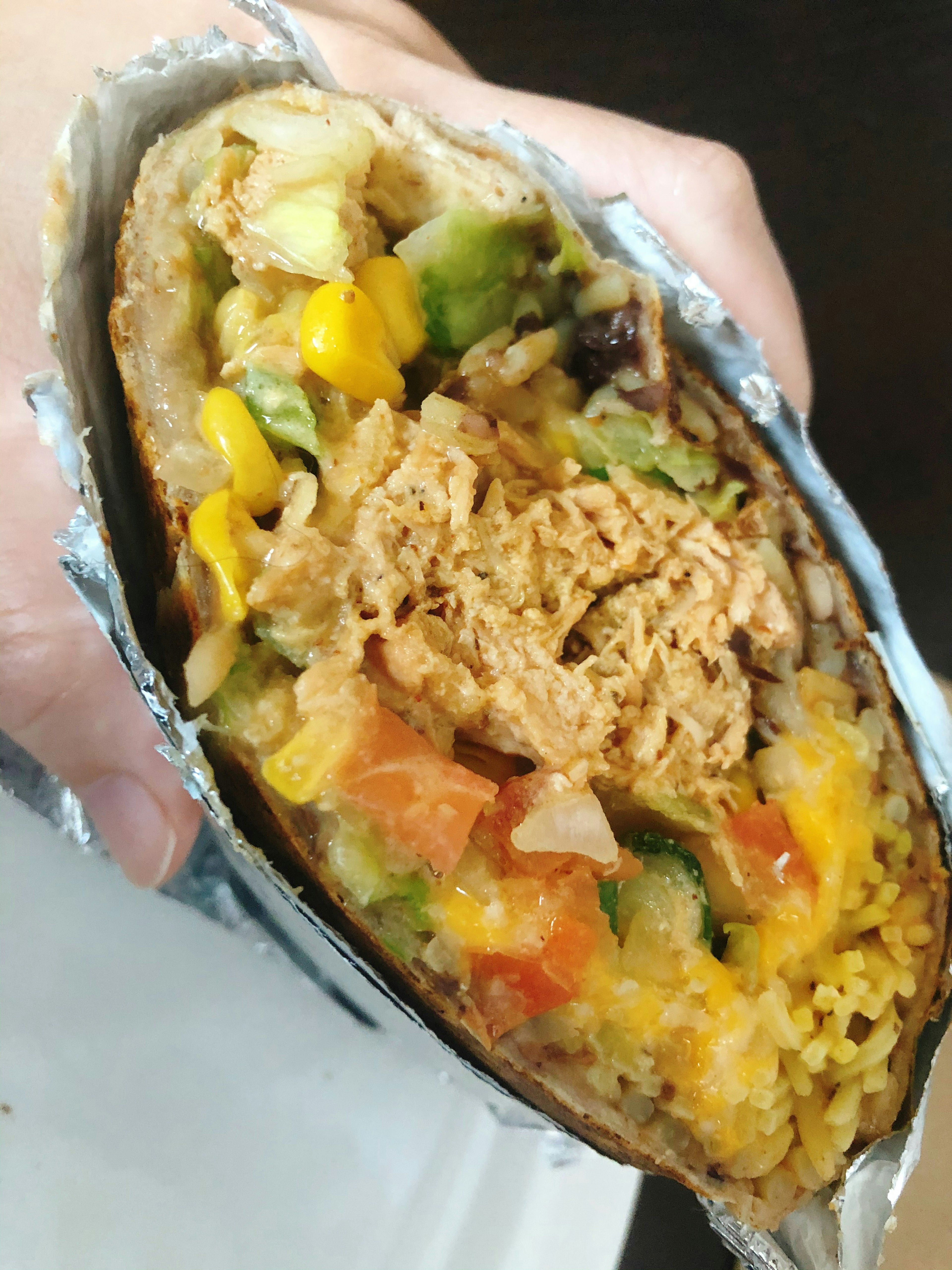 Potongan burrito yang mengenyangkan dipegang di tangan menunjukkan isian yang berwarna-warni