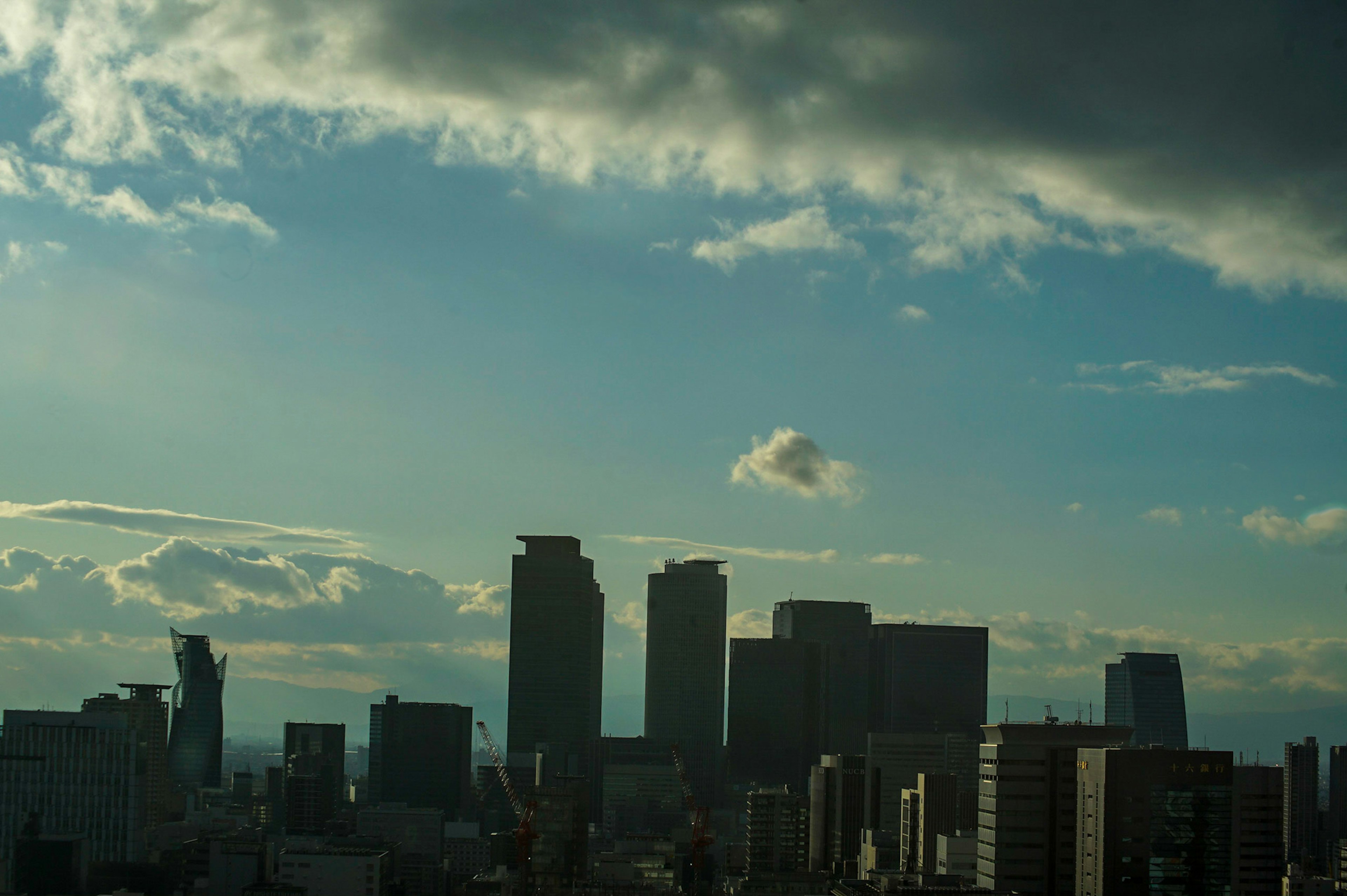 都市のシルエットと青い空に浮かぶ雲