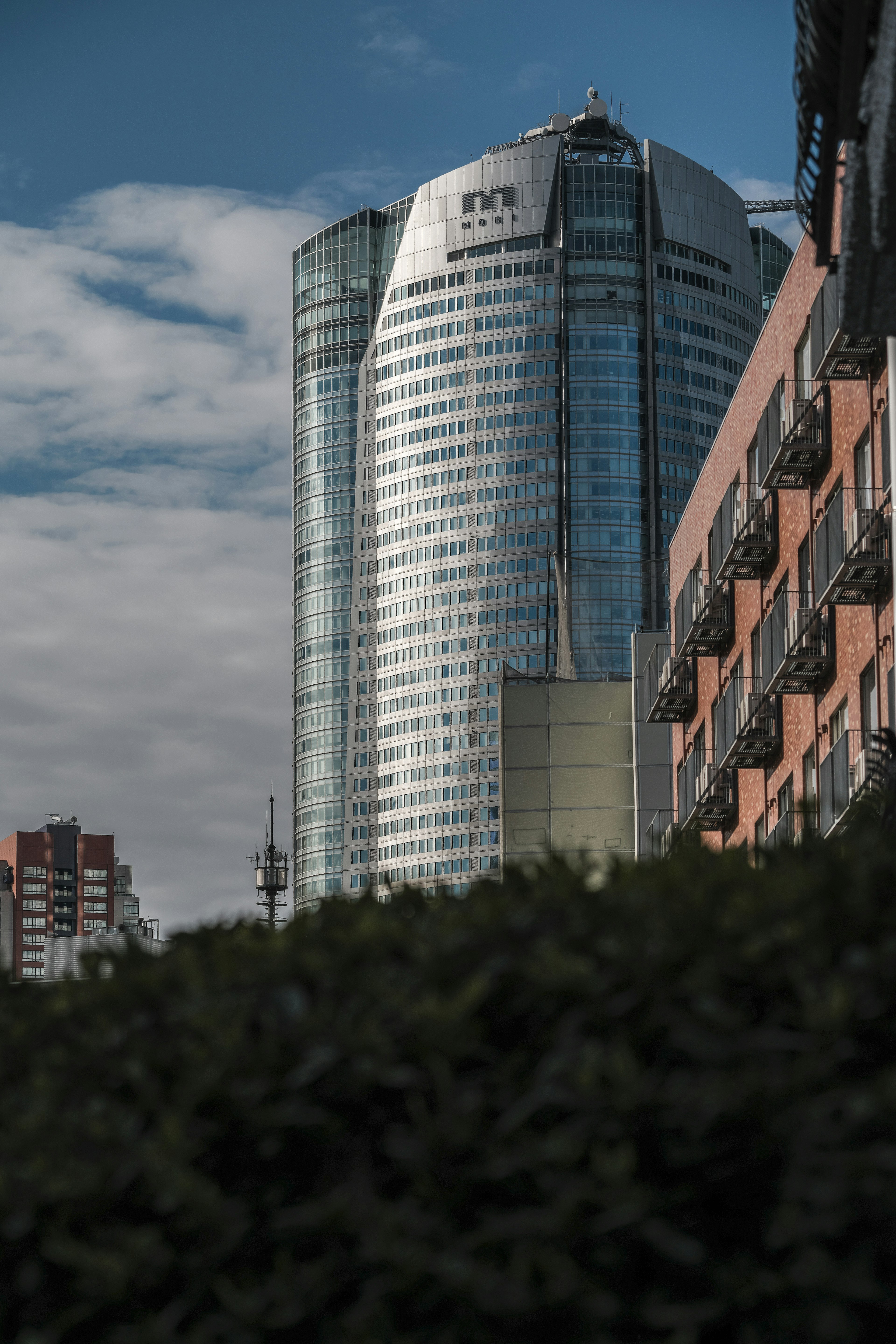 Skyscraper against a blue sky with visible balconies of nearby buildings