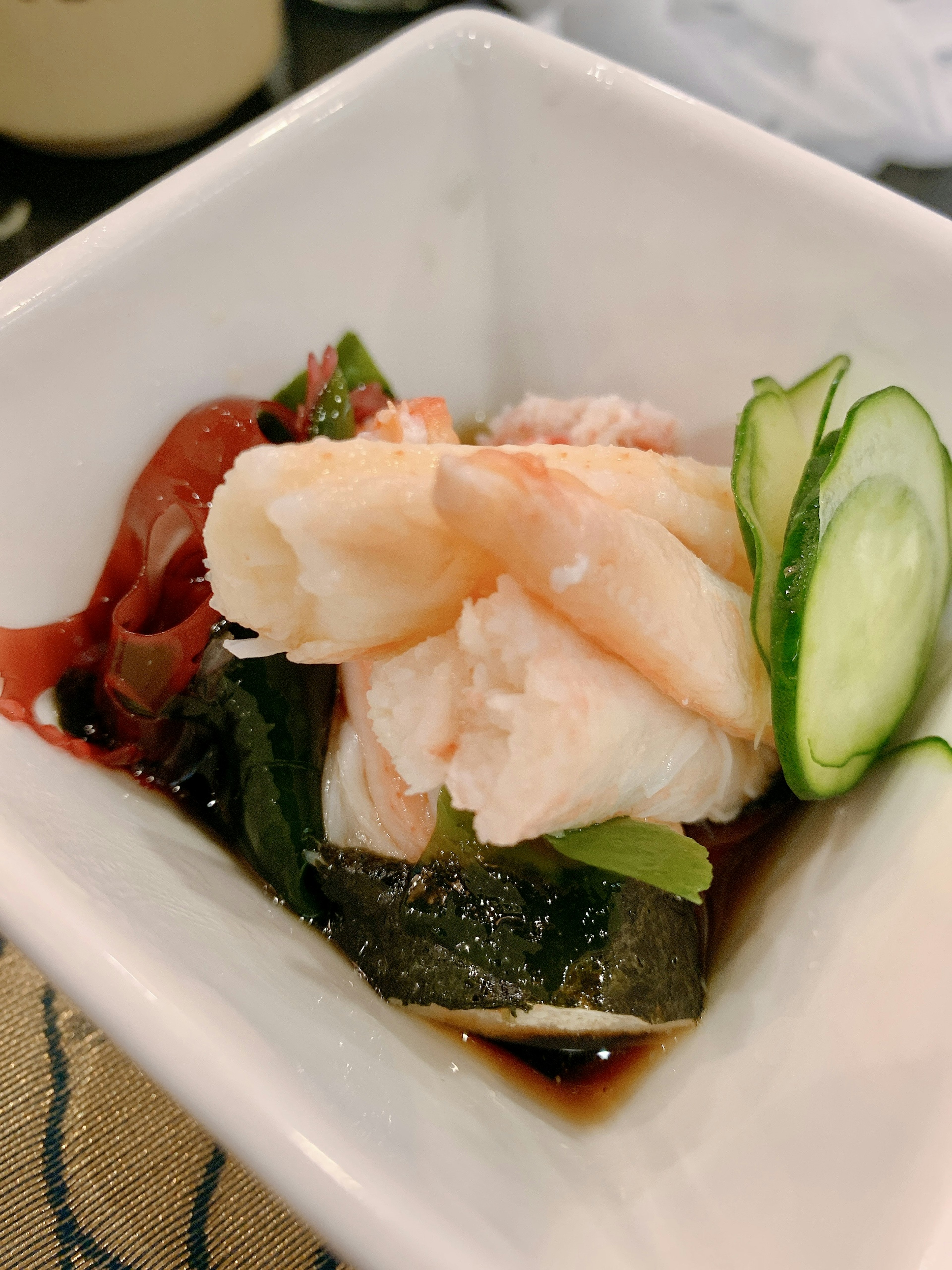 Sashimi of white fish with vegetables served in a small bowl with soy sauce