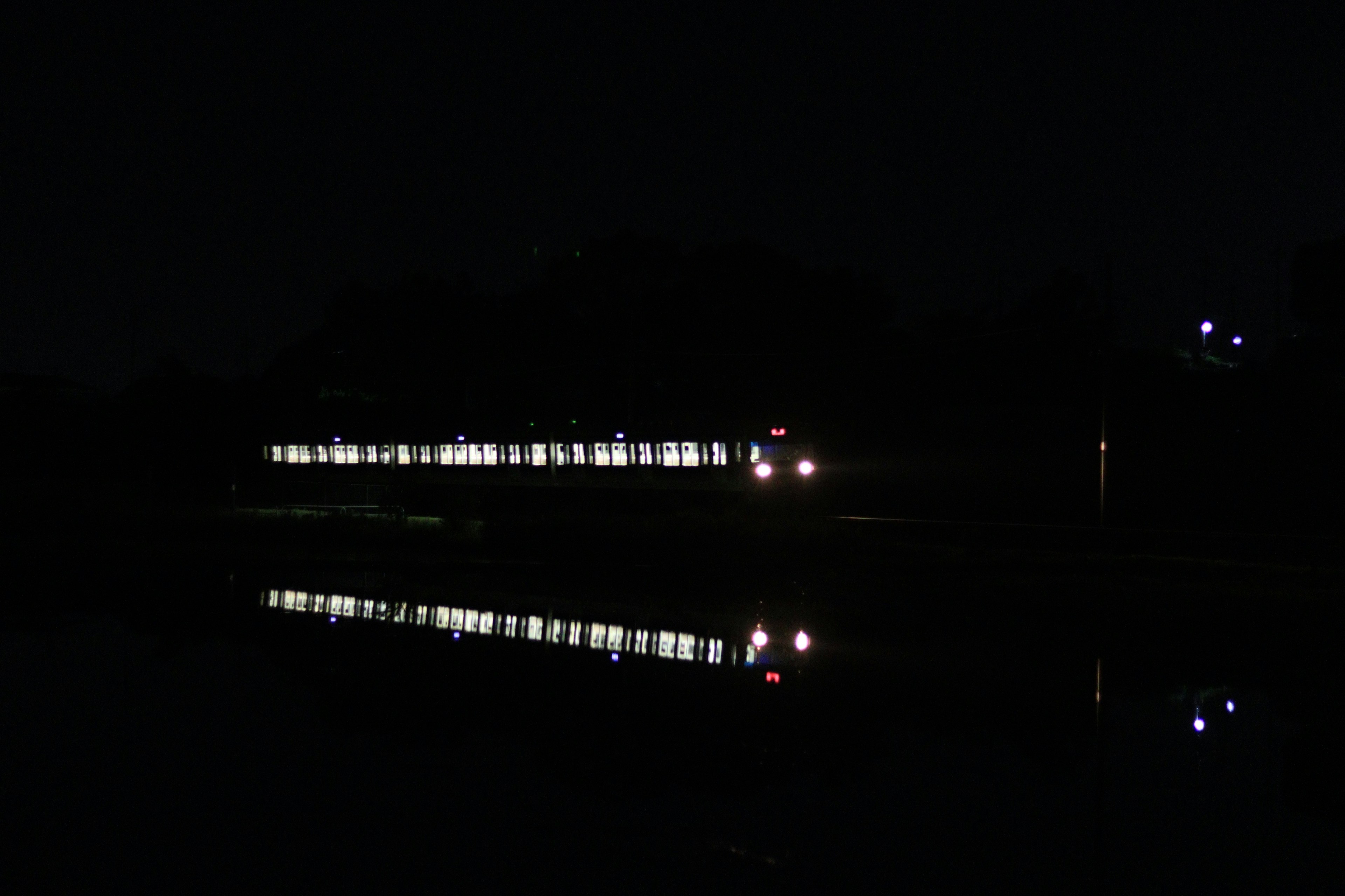 Luces del tren reflejándose en un lago oscuro