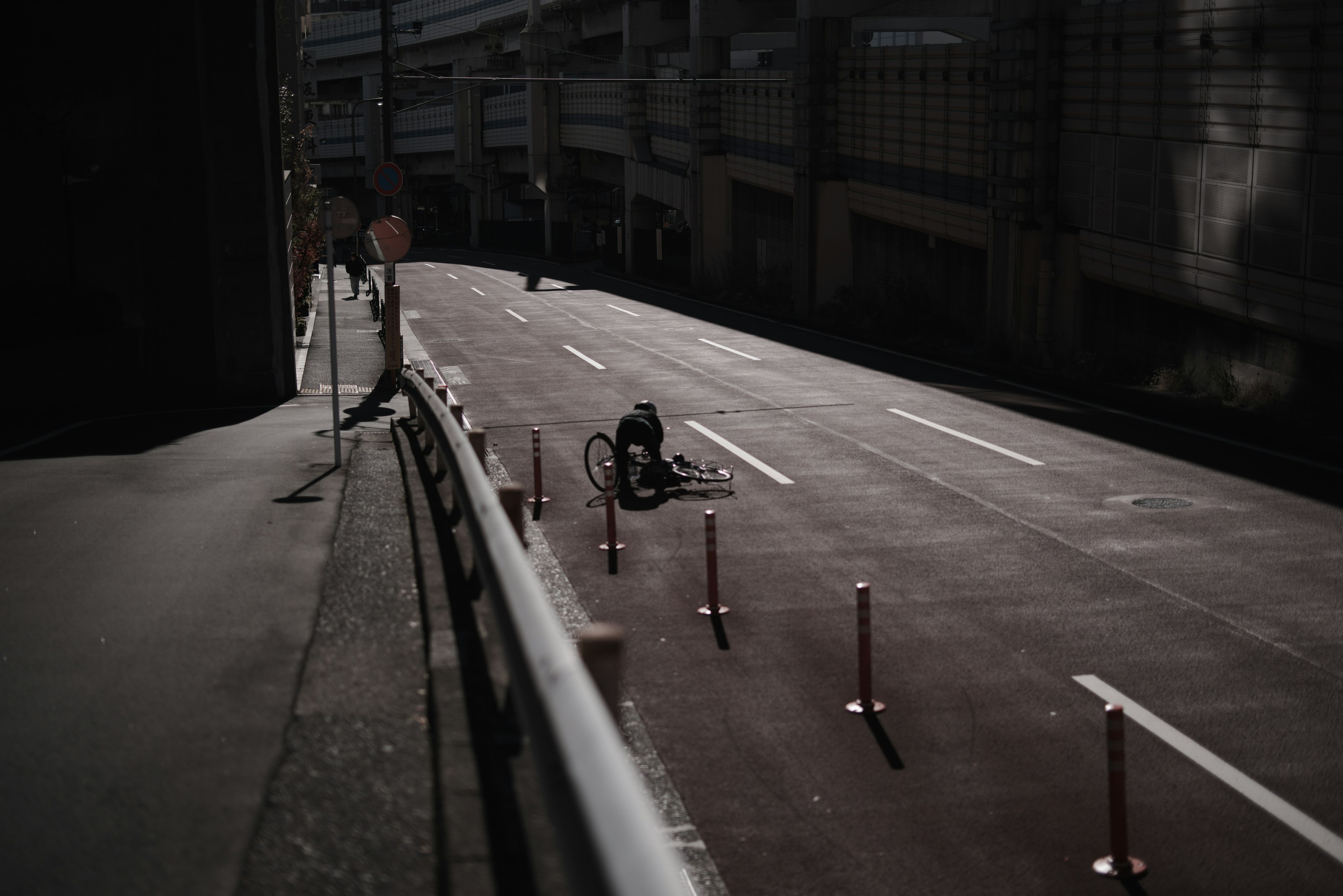 Empty street with a person working on the ground and traffic barriers