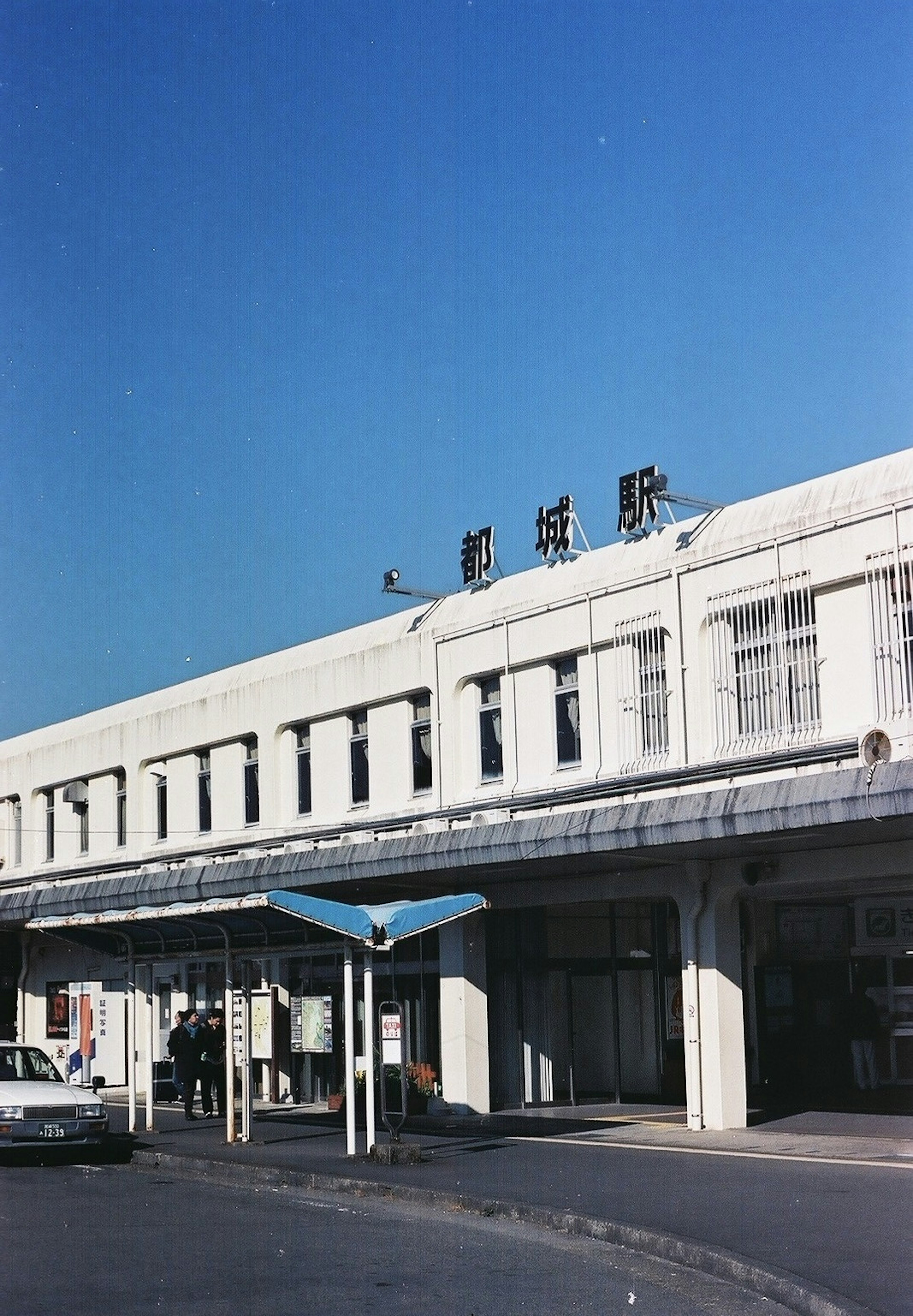 Bahnhofgebäude mit weißer Fassade und blauem Himmel sichtbares Stationsschild