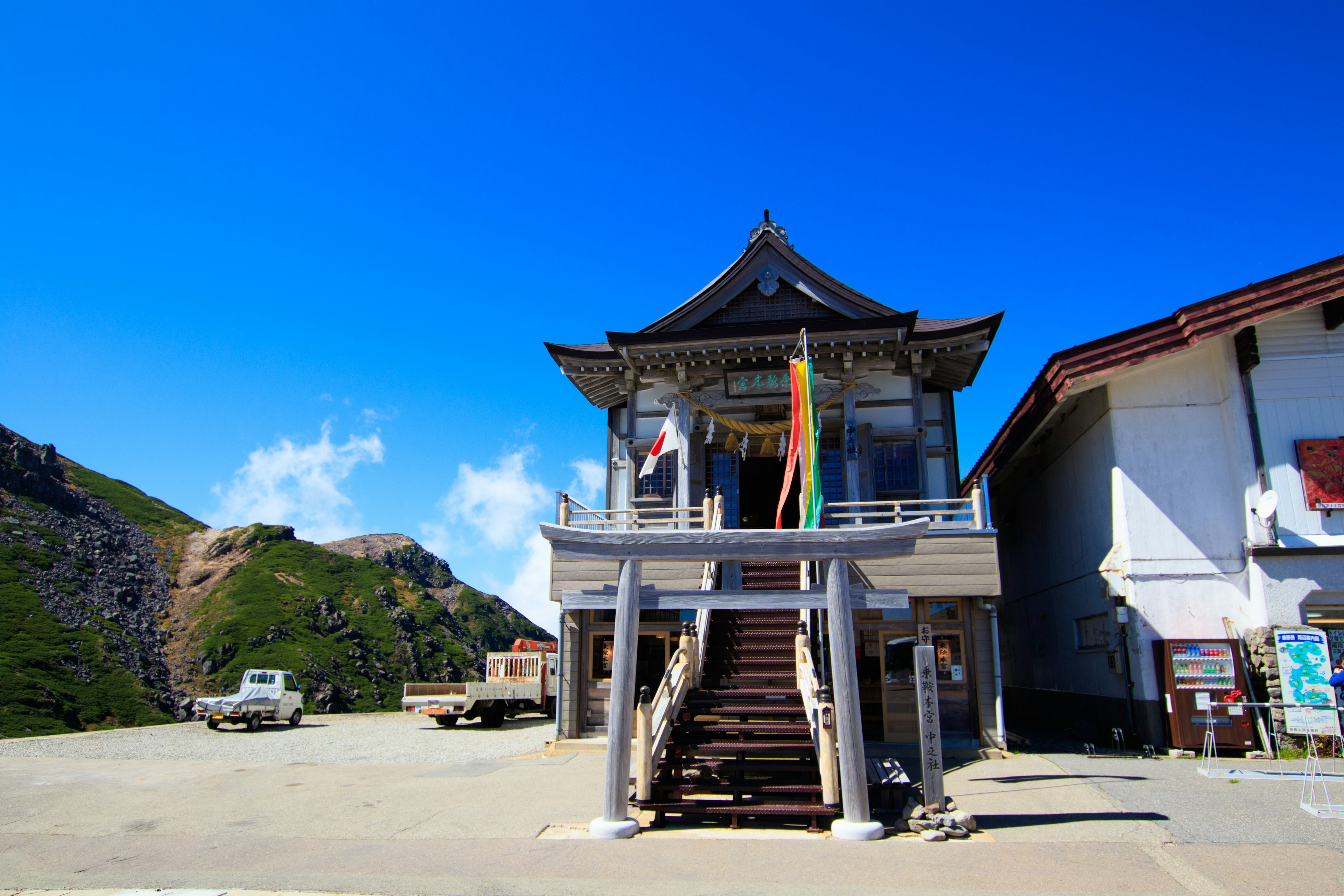 Traditionelles Gebäude mit bunten Fahnen vor einer Berglandschaft und klarem blauen Himmel