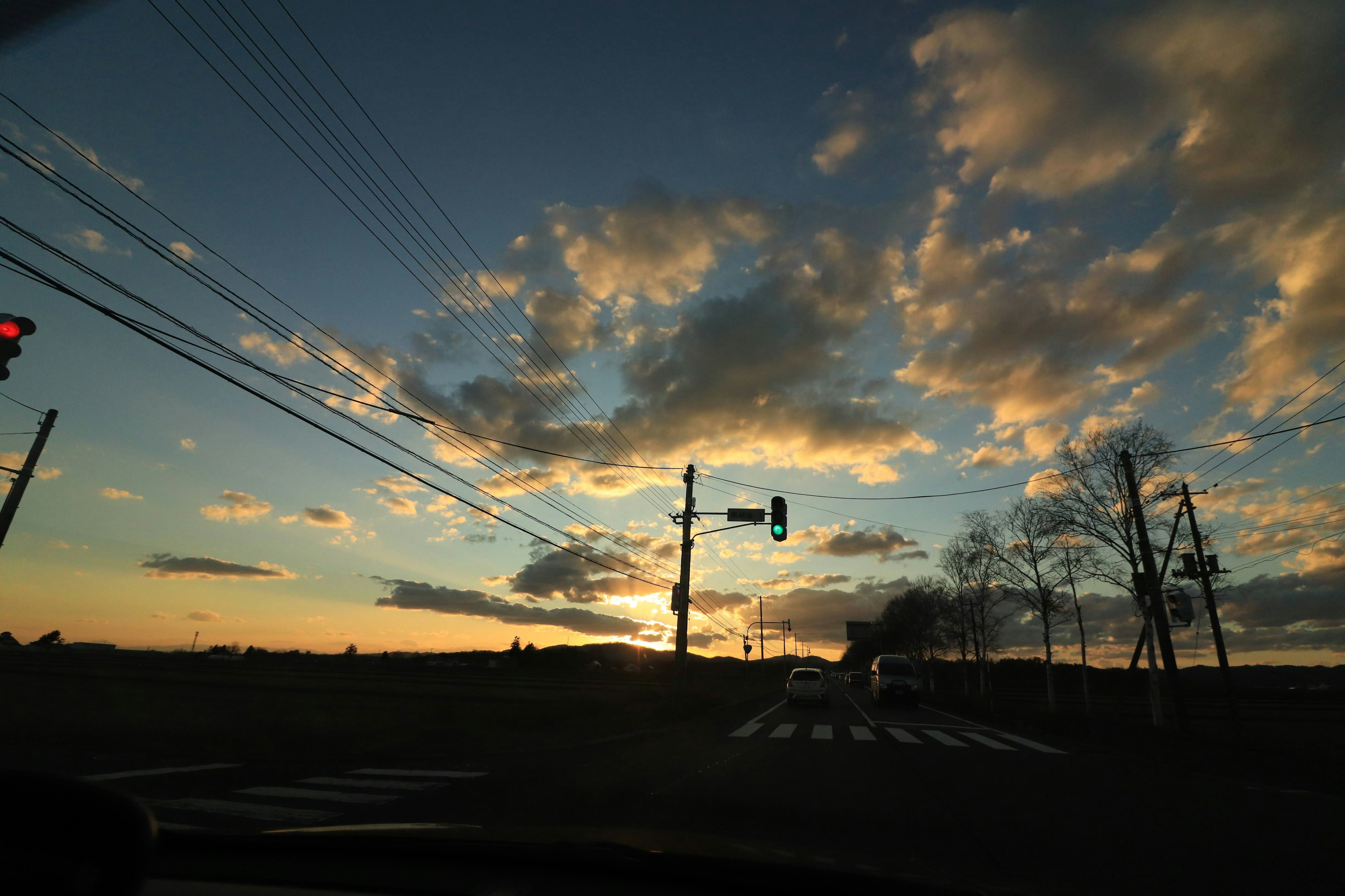 Pintoresco atardecer con nubes coloridas y semáforos visibles cerca de un paso peatonal