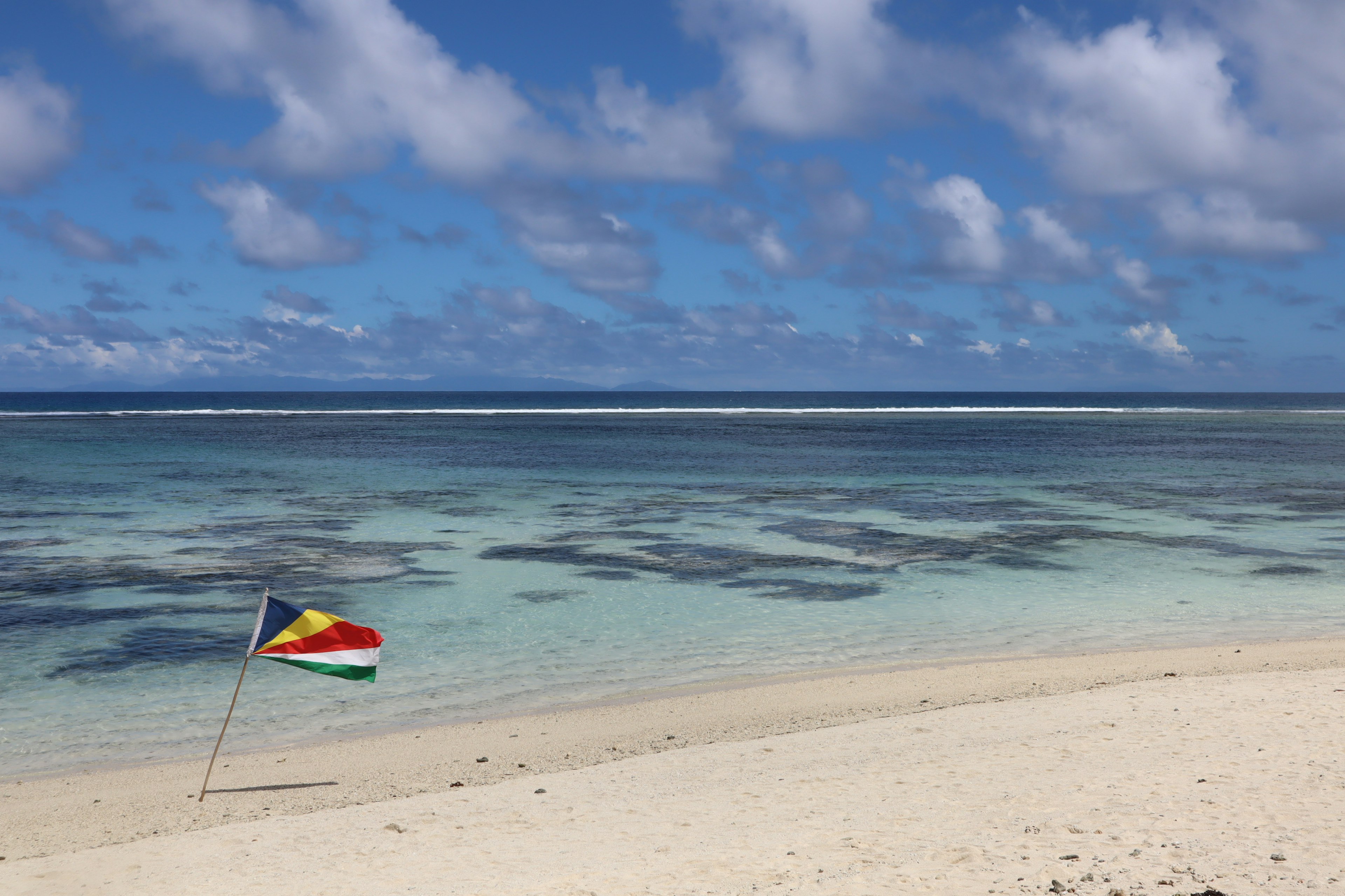 Scenic beach with blue ocean and a flag waving in the breeze