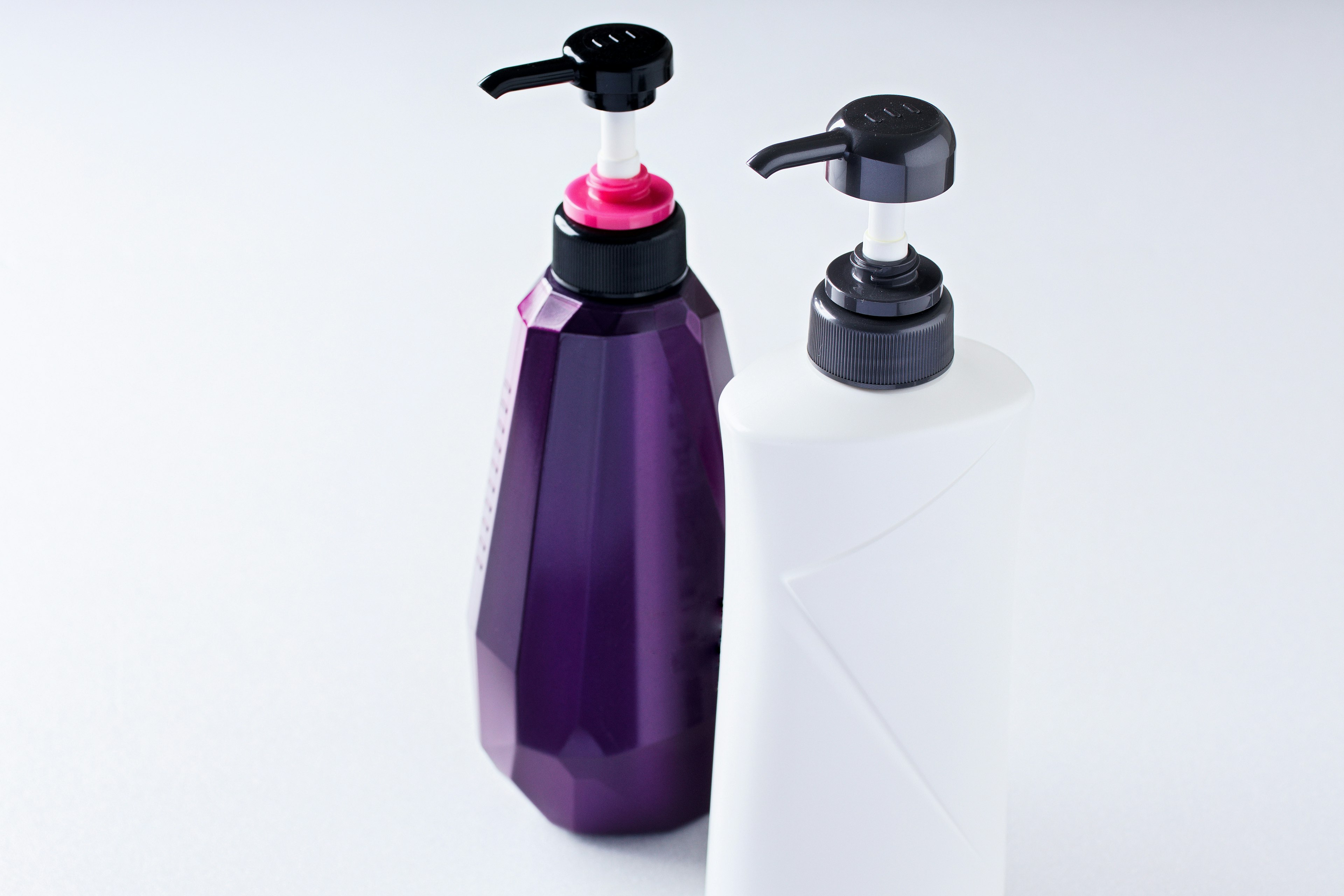 A purple geometric bottle and a white bottle with black pumps