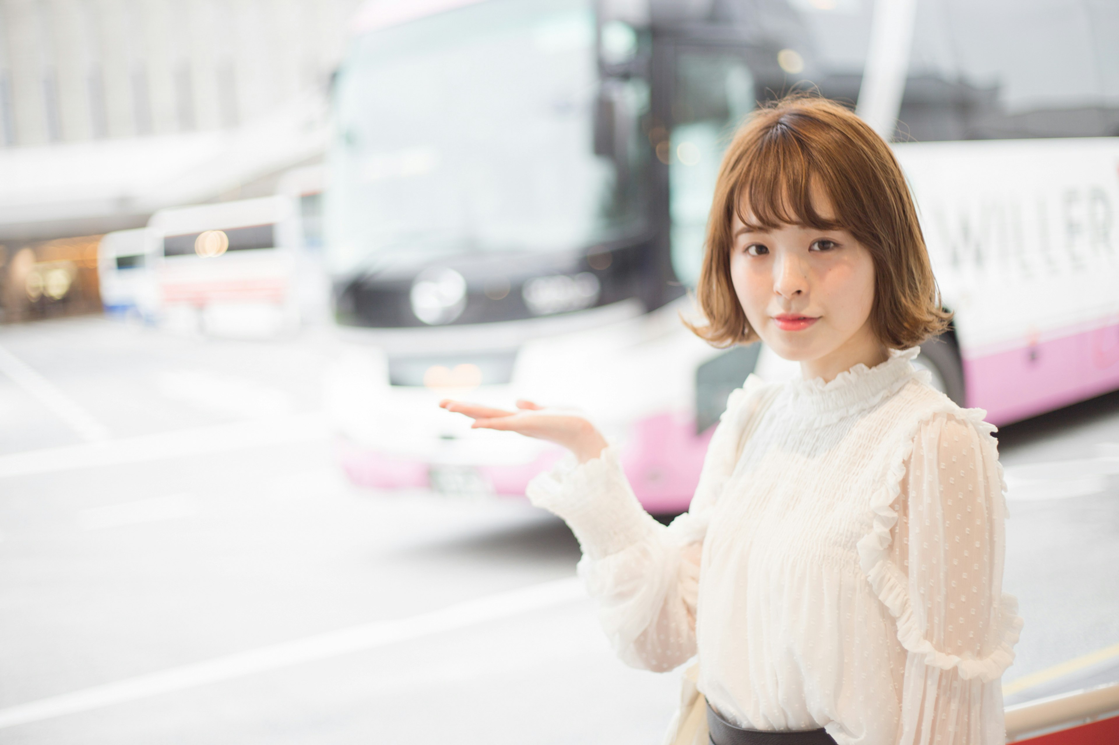 A woman gesturing towards a bus in a city setting