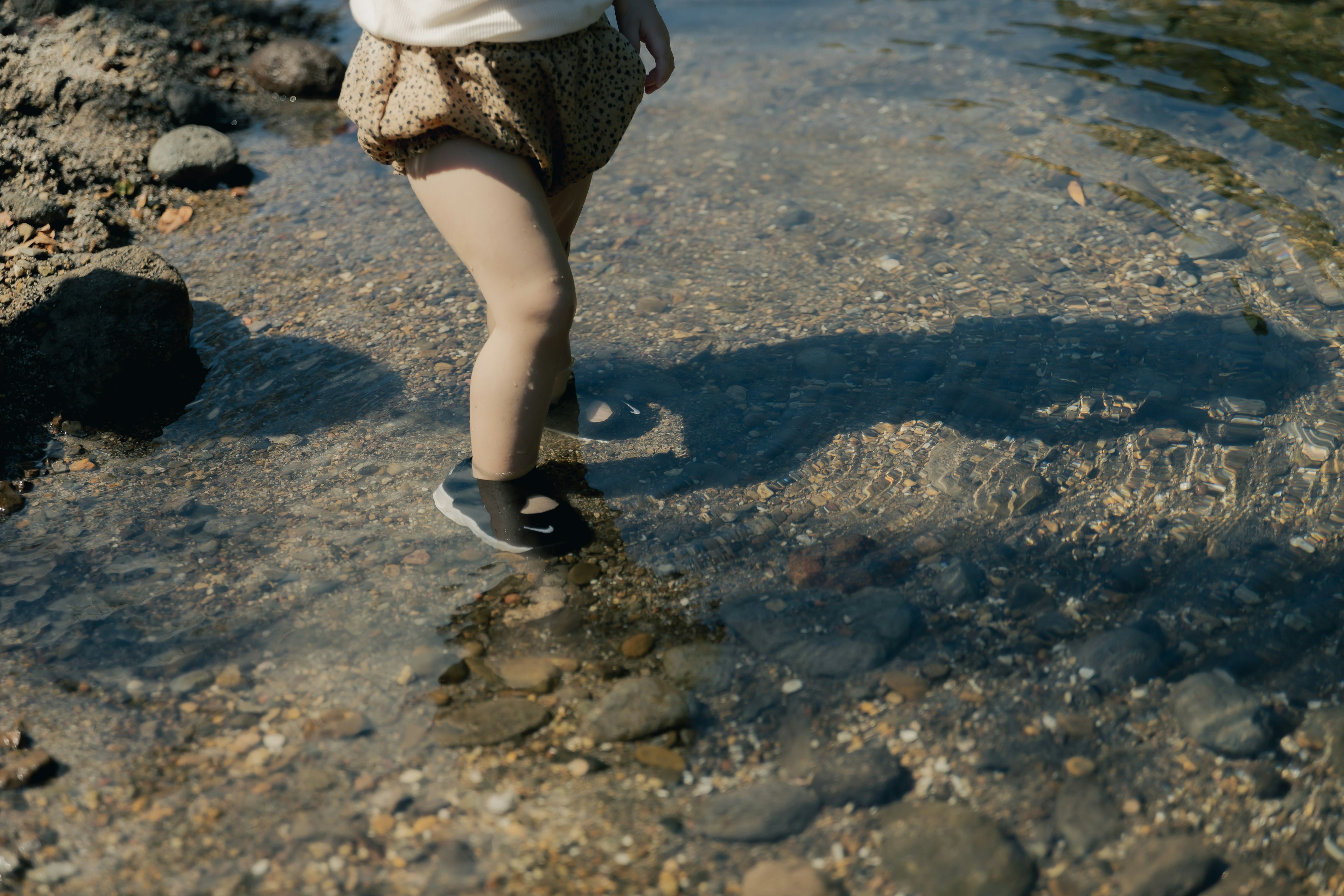 Pieds d'enfant pataugeant dans l'eau peu profonde au bord de l'eau